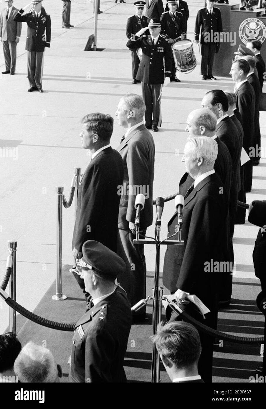 Ankunftszeremonie für Harold Macmillan, Premierminister von Großbritannien, 4:50pm Uhr. Ankunftszeremonien zu Ehren des britischen Premierministers Harold Macmillan. Auf der Überprüfungsplattform (L-R) stehen Präsident John F. Kennedy, Premierminister Macmillan, Botschafter der Vereinigten Staaten in Großbritannien, David K. E. Bruce, Staatssekretär Dean Rusk und Botschafter Großbritanniens, Sir David Ormsby-Gore (teilweise verborgen). In der Gruppe rechts von Botschafter Ormsby-Gore (von vorne nach hinten): Sekretär des Kabinetts von PMu2019s, Sir Norman Brook (meist versteckt); Stellvertretender stellvertretender Sekretär von Stockfoto