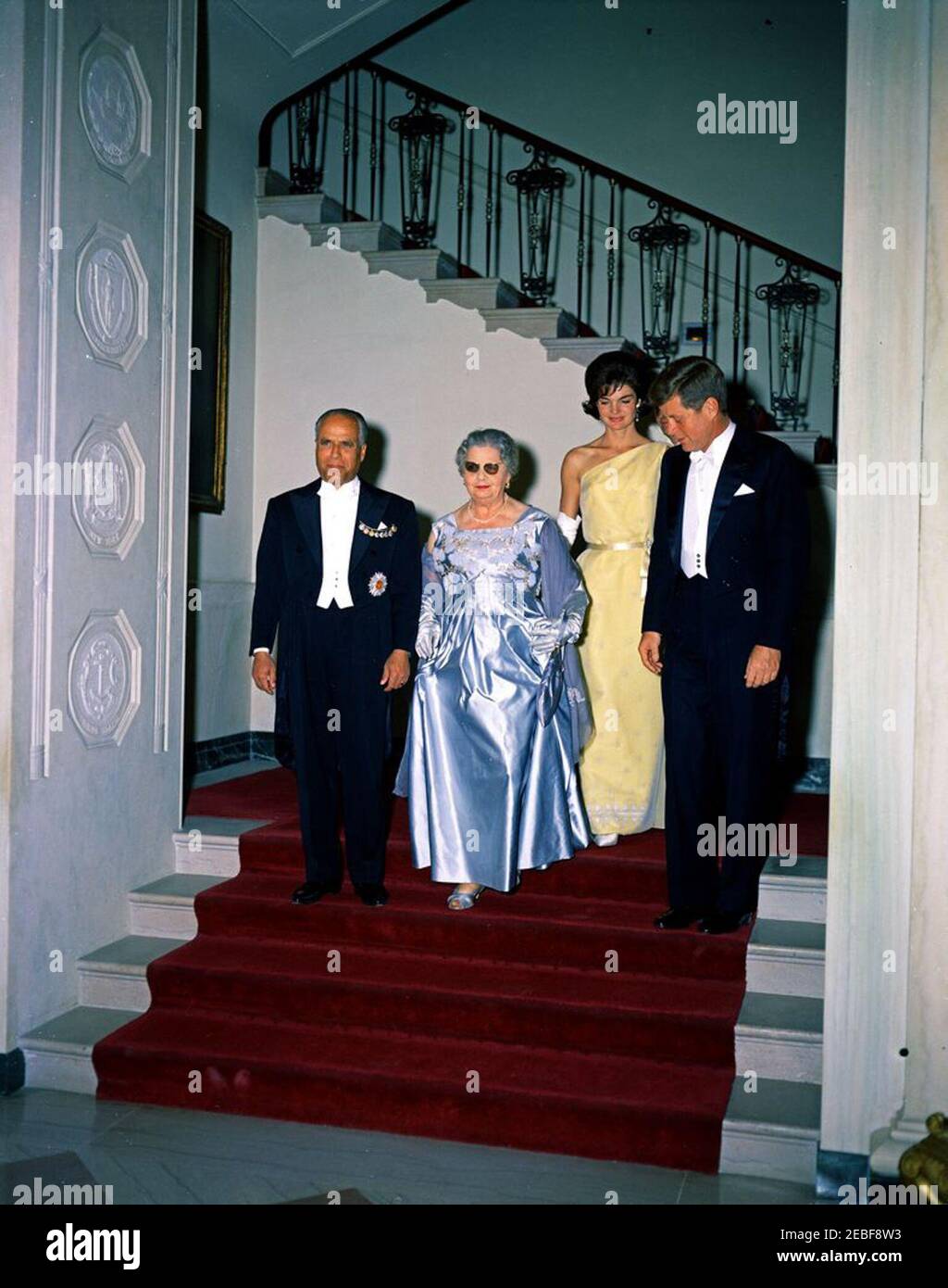 Abendessen zu Ehren von Habib Bourguiba, Sr., Präsident von Tunesien, 8:00pm Uhr. Abendessen zu Ehren von Habib Bourguiba, Sr., Präsident von Tunesien. Die große Treppe hinunter zur Eingangshalle, L-R: Präsident Bourguiba; First Lady von Tunesien, Moufida Bourguiba (früher Mathilde Lorrain); First Lady Jacqueline Kennedy; Präsident John F. Kennedy. White House, Washington, D.C. Stockfoto