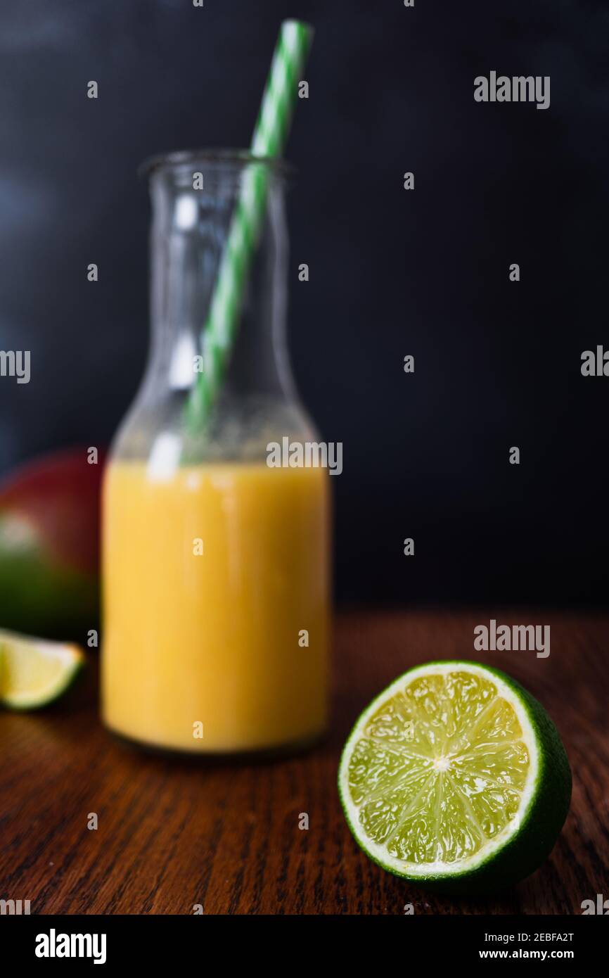 Aufnahme von Getränken mit frischem Obst-Smoothie im Hintergrund ohne Fokus mit frischem und jiukoj Limettensegment im Vordergrund. Dunkel b Stockfoto
