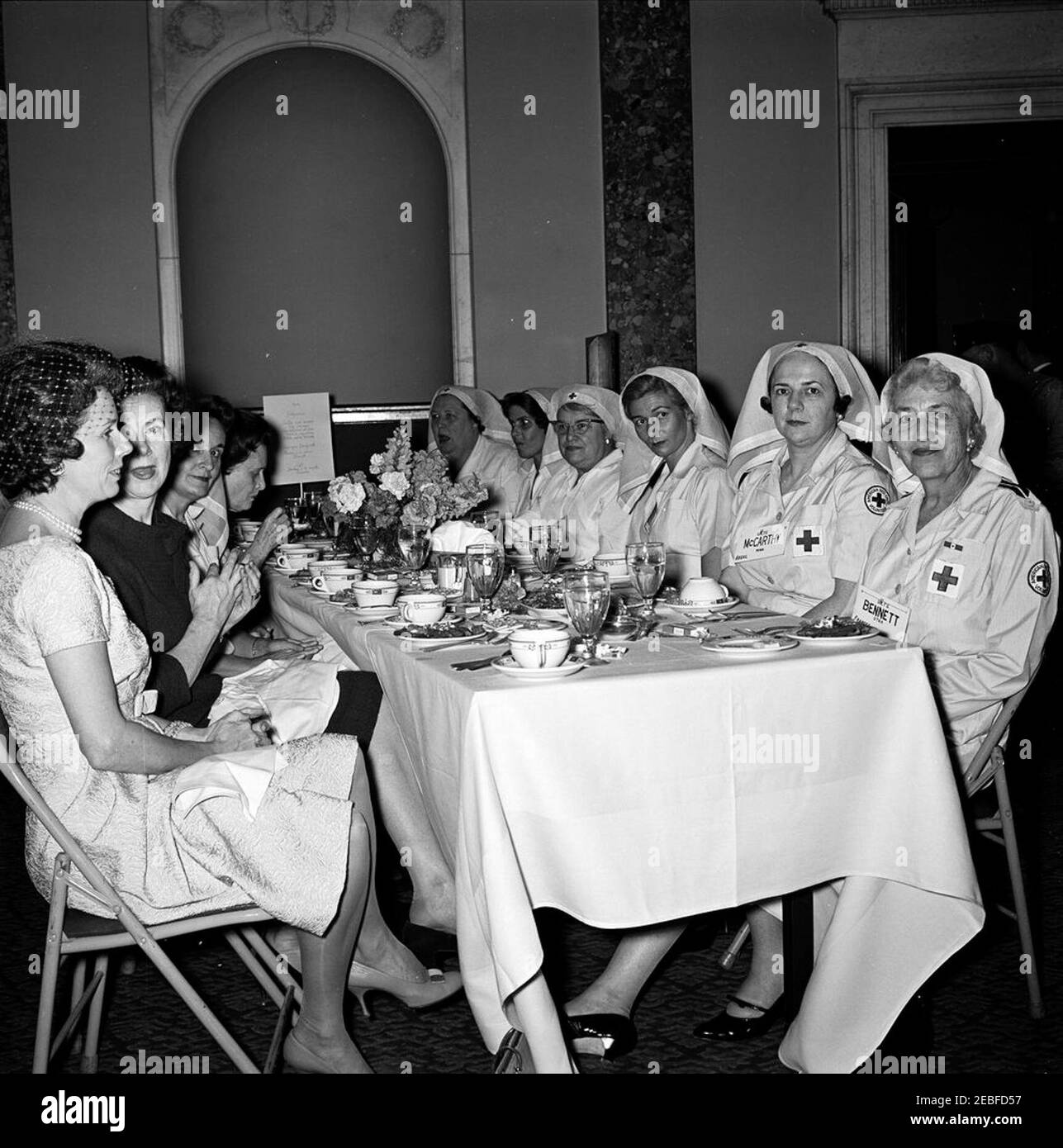First Lady Jacqueline Kennedy (JBK) nimmt an der Senate Ladies Red Cross Unit Lunch Teil. Mitglieder des Senats Damen Rotes Kreuz Einheit besuchen ein Mittagessen in der Old Supreme Court Chamber, United States Capitol Building, Washington, D.C. die Rotes Kreuz Einheit (auch bekannt als u201cLadies der Senateu201d) besteht aus den Frauen von Mitgliedern des US-Senats. Von links nach rechts: Phyllis Ellsworth Dillon (Frau des Sekretärs des Schatzamtes, C. Douglas Dillon); zwei nicht identifizierte Frauen; Ivo Sparkman (Frau des Senators John J. Sparkman von Alabama); Mary Katherine Babb Randolph (Frau von Senator Jennings Randolph o Stockfoto