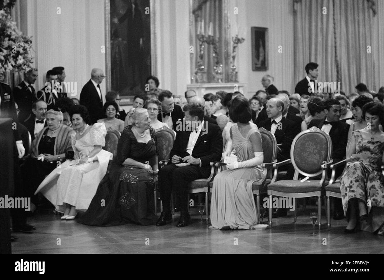 Abendessen zu Ehren der Nobelpreisträger, 8:00pm Uhr. Präsident John F. Kennedy und andere treffen sich im East Room, um bei einer Lesung des Schauspielers Frederic March von Auszügen aus den Werken der späten amerikanischen Nobelpreisträger während eines Abendessens zu Ehren der Nobelpreisträger aus der westlichen Hemisphäre teilzunehmen. Präsident Kennedy und First Lady Jacqueline Kennedy besuchen mit der Nobelpreisträgerin Pearl S. Buck. Platz in der ersten Reihe (L-R): Vizepräsident Lyndon B. Johnson (meist versteckt); Katherine Tupper Marshall (Witwe des Nobelpreisträgers und ehemaligen Staatssekretärs, General George C. Marshall); Lady Bird Stockfoto