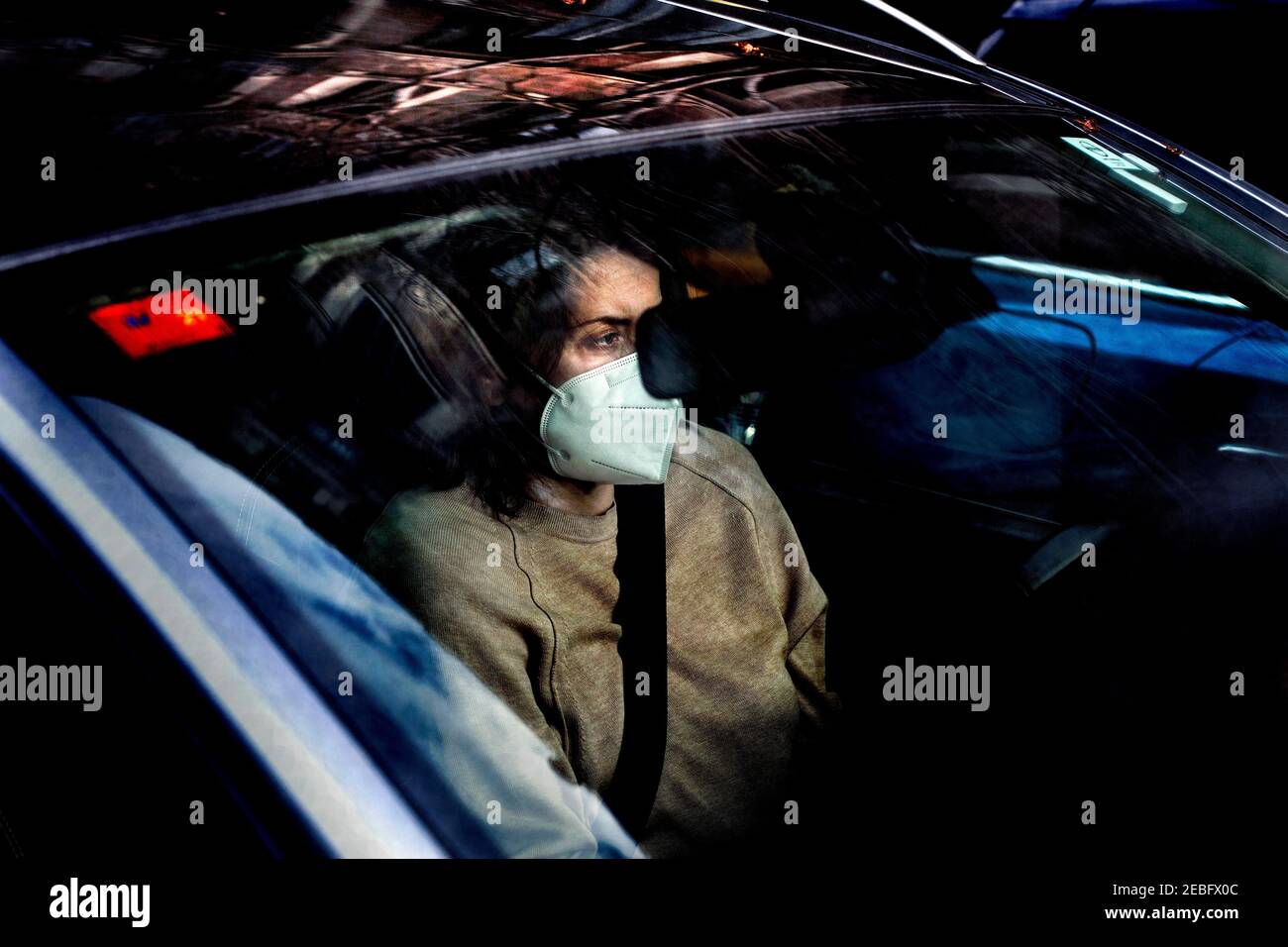 Frau, die Auto fährt und Gesichtsmaske trägt, Barcelona, Spanien. Stockfoto