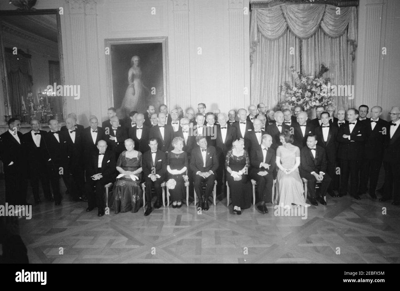 Abendessen zu Ehren der Nobelpreisträger, 8:00pm Uhr. Präsident John F. Kennedy und First Lady Jacqueline Kennedy posieren mit Nobelpreisträgern aus der westlichen Hemisphäre bei einem Abendessen zu ihren Ehren. Sitzend (L-R): Dr. Georg von Bu00e9ku00e9sy von der Harvard University; Autor Pearl S. Buck; Dr. Rudolf L. Mu00f6ssbauer vom California Institute of Technology; Autorin Mary Welsh Hemingway; Präsidentin Kennedy; Katherine Tupper Marshall; Dr. Melvin Calvin von der University of California, Berkeley; Frau Kennedy; und Dr. Robert Hofstadter von der Stanford University. Ebenfalls im Bild: United Nations (UN) und Stockfoto