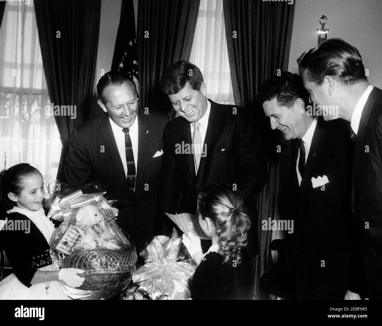 Besuch von Vertretern der Aktionsgruppe Ostersiegel, 12:25pm Uhr. Besuch von Vertretern der Ostersiegelkampagne. Ostersiegel Zwillinge, Paula und Patricia Webber (Sumter, South Carolina); National Easter Seal Chairman Art Linkletter; Präsident John F. Kennedy; Präsident der National Society for Crippled Children and Adults, Joseph Foss (Sioux Falls, South Dakota); Gouverneur von South Carolina Ernest Hollings. Oval Office, White House, Washington, D.C. Stockfoto