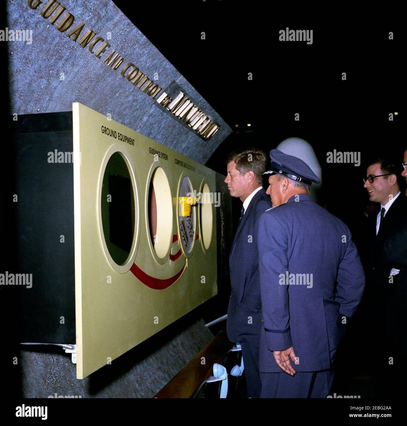 Reise nach Kalifornien: Vandenberg Air Force Base, 4:08pm Uhr. Präsident John F. Kennedy betrachtet das Führungs- und Kontrollsystem für die Minuteman-Rakete während einer Tour durch Raumschiffe in einem Hangar auf der Vandenberg Air Force Base, Kalifornien. Von links nach rechts: Präsident Kennedy; Kommandant des strategischen Luftkommandos, General Thomas S. Power; Direktor für Forschung und Entwicklung für das Verteidigungsministerium, Dr. Harold Brown. Stockfoto