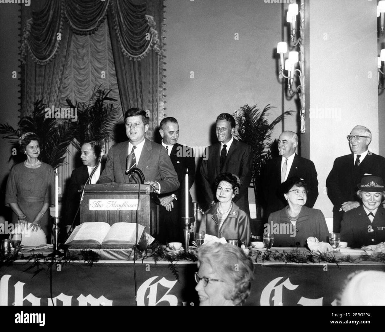 Bemerkungen beim Nationalen Gebetsfrühstück 1961, 9:37am Uhr. Gebetsfrühstück, das vom Internationalen Rat für christliche Führung im East Room, Mayflower Hotel, Washington, D.C. gesponsert wird, spricht Präsident John F. Kennedy die Frauen beim Gebetsfrühstück in einem separaten Raum des Hotels an. Ganz links ist der Co-Vorsitzende des Frühstücks Gladys Johnston (Ehefrau von Senator Olin Johnston aus South Carolina); rechts vom Präsidenten sind Vizepräsident Lyndon B. Johnson und Reverend Billy Graham; Lady Bird Johnson sitzt vor Reverend Graham; Gründer und Geschäftsführer von International Christian Lead Stockfoto