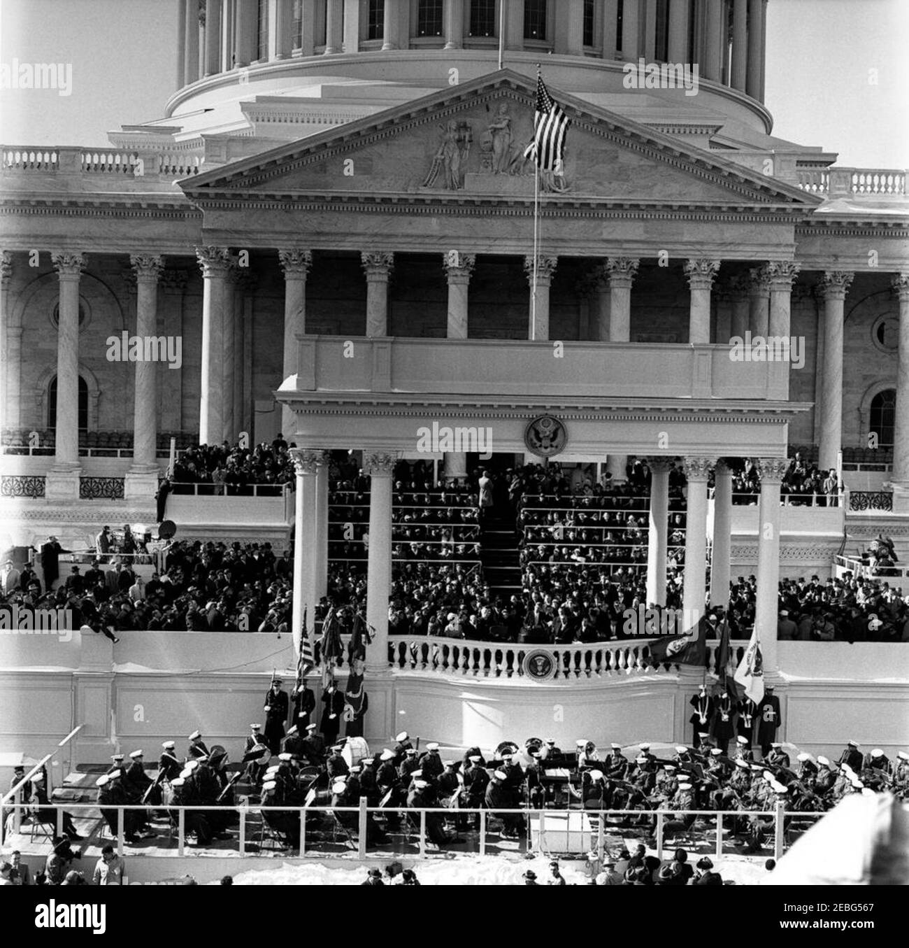 Eröffnungszeremonien im US-Kapitol und Eröffnungsparade. Einweihung von John F. Kennedy im East Portico, Kapitolgebäude der Vereinigten Staaten, Washington, D.C. Präsident John F. Kennedy hält Antrittsrede. Blick auf: Vizepräsident Lyndon B. Johnson; ehemaliger Vizepräsident Richard M. Nixon; ehemaliger Präsident Harry S. Truman; ehemalige First Lady Bess Truman; ehemaliger Präsident Dwight D. Eisenhower; ehemalige First Lady Mamie Eisenhower; First Lady Jacqueline Kennedy; Lady Bird Johnson; Joseph P. Kennedy, Sr.; und Rose Fitzgerald Kennedy. United States Marine Band auf Plattform unter Antrittsstand. Stockfoto