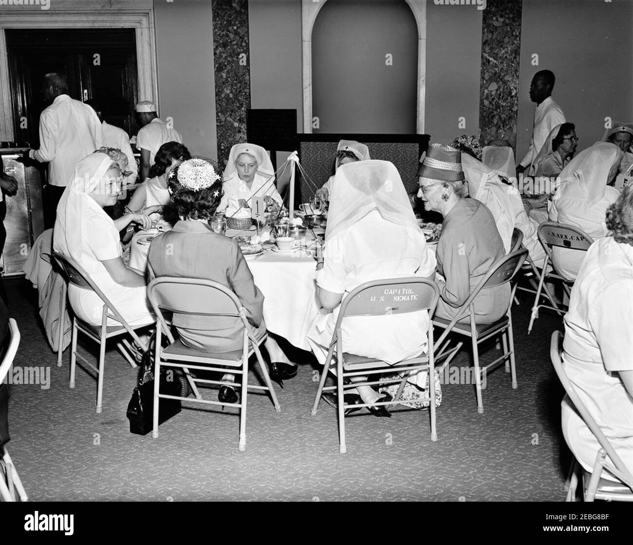 First Lady Jacqueline Kennedy (JBK) nimmt am Mittagessen der Rotkreuzeinheit des Senats Ladiesu0027 Teil. Mitglieder des Senats Damen Rotes Kreuz Einheit sitzen an einem Tisch während eines Mittagessenes (besucht von First Lady Jacqueline Kennedy) in der Old Supreme Court Chamber, United States Capitol Building, Washington, D.C. das Rote Kreuz Einheit (auch bekannt als u201cLadies der Senateu201d) Besteht aus den Ehefrauen von Mitgliedern des US-Senats. Die am Tisch im Vordergrund sitzen gehören: Phyllis Ellsworth Dillon (links, Gesicht verdeckt), Frau des Sekretärs der Schatzkammer, C. Douglas Dillon; Opal Warren Yarborough (links c Stockfoto