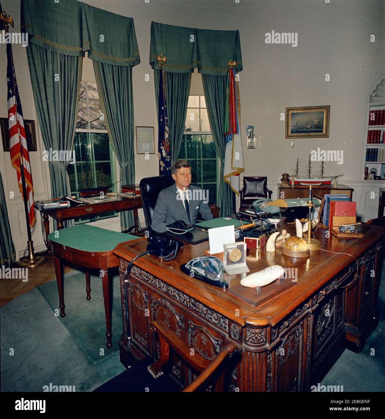 Präsident Kennedy an seinem Schreibtisch. Präsident John F. Kennedy sitzt an seinem Schreibtisch (HMS Resolute Desk) im Oval Office des Weißen Hauses, Washington, D.C. Stockfoto