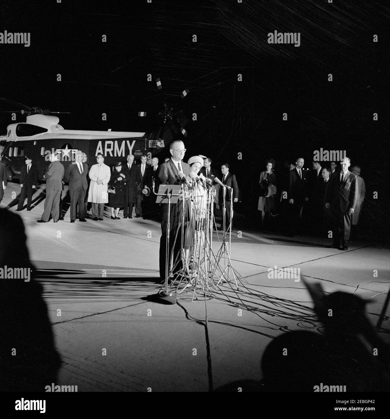 Rückkehr zur Andrews Air Force Base; Leiche des Präsidenten Kennedyu0027s im Krankenwagen; Präsident Johnson spricht zu der Nation. Präsident Lyndon B. Johnson (bei Mikrofonen) gibt der Nation nach seinem Amtseid an Bord der Air Force One und seiner Ankunft auf der Andrews Air Force Base in Maryland Bemerkungen; First Lady Bird Johnson steht neben Präsident Johnson. Ebenfalls im Bild: Stellvertretender Pressesprecher, Malcolm Kilduff; Sprecher des Repräsentantenhauses, John W. McCormack (Massachusetts); Vertreter Cornelius E. Gallagher (New Jersey); Vertreter Carl Vinson (Georgia); Repräsentanten Stockfoto