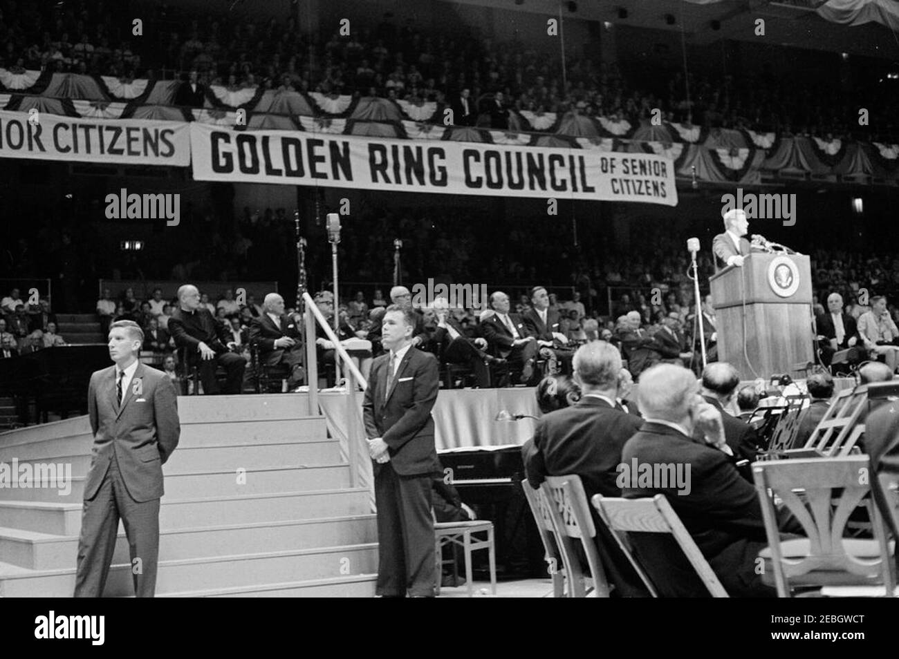Ausflug nach New York City: Madison Square Garden, Sr. Citizens Rally, 4:00pm Uhr. Präsident John F. Kennedy (an einem Rednerpult) hält Bemerkungen während einer Kundgebung über die medizinische Versorgung für ältere Menschen, die vom National Council of Senior Citizens und dem Golden Ring Council of Senior Citizens im Madison Square Garden gesponsert wird. Zu den auf der Bühne sitzenden Personen gehören: Präsident der American Federation of Labor and Congress of Industrial Organizations (AFL-CIO), George Meany; Präsident der International Ladies Garment Workersu2019 Union, David Dubinsky; Sekretär für Gesundheit, Bildung und Wohlfahrt, Abraham Ribicoff. Als Stockfoto