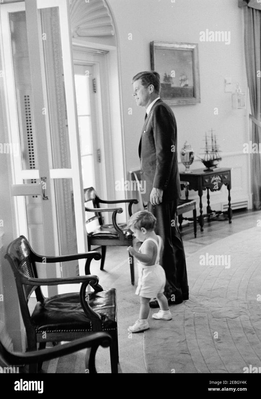 Präsident Kennedy mit John F. Kennedy, Jr. (JFK, Jr.). Präsident John F. Kennedy steht mit seinem Sohn, John F. Kennedy, Jr., an einer offenen Tür im Oval Office, White House, Washington, D.C. Stockfoto
