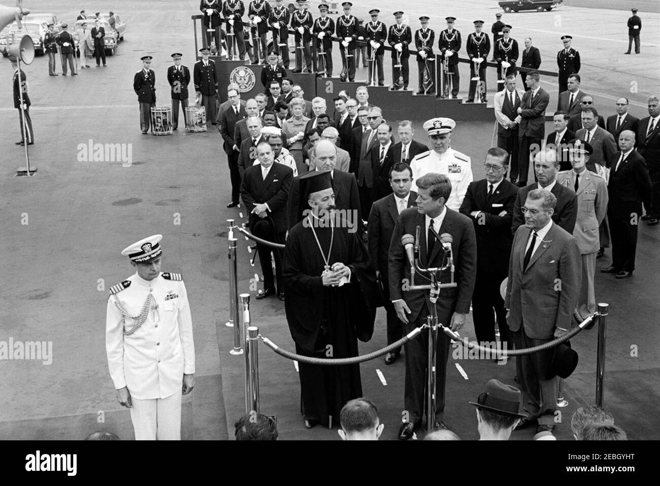 Zeremonie zur Ankunft von Erzbischof Makarios III., Präsident von Zypern, 11:00am Uhr. Präsident John F. Kennedy (bei Mikrofonen) hält Bemerkungen bei der Ankunft Zeremonien zu Ehren des Präsidenten der Republik Zypern, Erzbischof Makarios III.. Auf der Überprüfungsplattform (L-R): Erzbischof Makarios III; US-Außenminister Dean Rusk; Außenminister der Republik Zypern, Spyros Kyprianou; Präsident Kennedy; Leiter der Marineoperationen, Admiral George W. Anderson, Jr. (U.S.N.); US-Botschafter in Zypern, Fraser Wilkins; US-Protokollchef, Angier Biddle Duke; Und Botschafter der Stockfoto