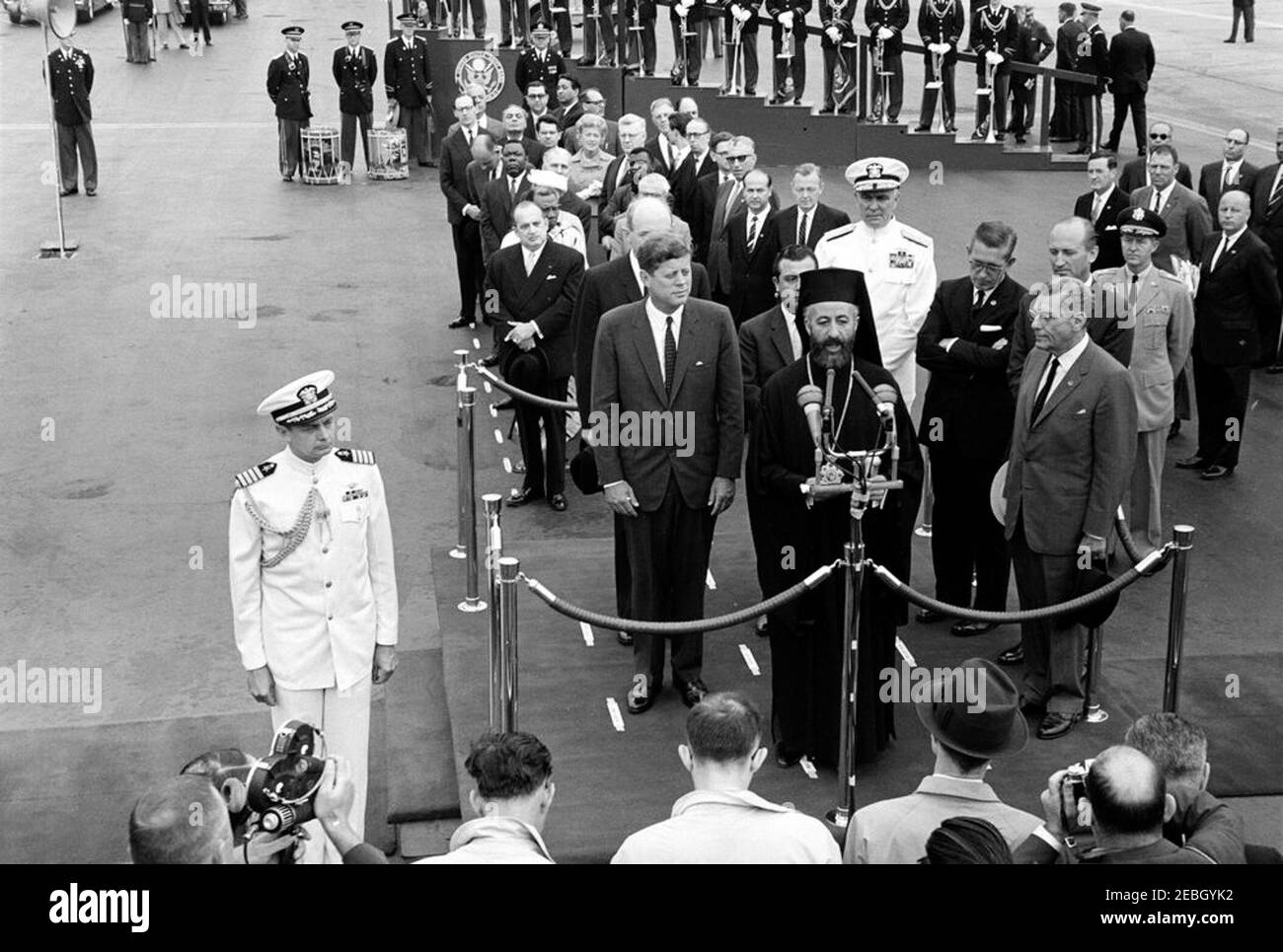 Zeremonie zur Ankunft von Erzbischof Makarios III., Präsident von Zypern, 11:00am Uhr. Der Präsident der Republik Zypern, Erzbischof Makarios III., hält zu seinen Ehren bei den Ankunftszeremonien eine Rede. Auf der Überprüfungsplattform (L-R): US-Außenminister Dean Rusk (hinten, teilweise versteckt); Präsident John F. Kennedy; Außenminister der Republik Zypern, Spyros Kyprianou (teilweise versteckt); Erzbischof Makarios III (an Mikrofonen); Leiter der Marineoperationen, Admiral George W. Anderson, Jr. (U.N.); US-Botschafter in Zypern, Fraser Wilkins; US-Chef des Protokolls, Angier Stockfoto