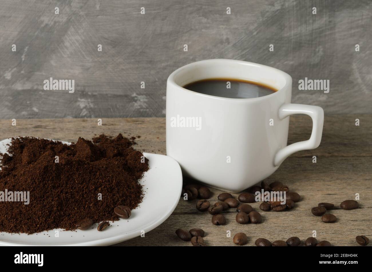 Eine Tasse Kaffee mit Kaffeebohnen und gemahlenem Kaffee auf einer Untertasse. Selektiver Fokus. Stockfoto