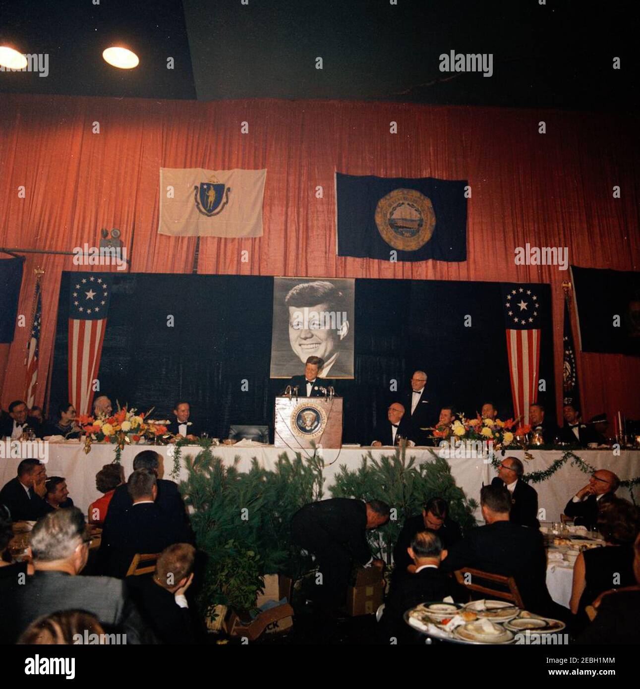 Reise nach Maine u0026 Massachusetts: Boston, Fundraising Dinner im Commonwealth Armory, 8:13pm Uhr. Präsident John F. Kennedy (am Rednerpult) hält Bemerkungen während des u201cAll New England Salute Dinneru201d zu seinen Ehren im Commonwealth Armory in Boston, Massachusetts. An der Spitze sitzen unter anderem: Sprecher des Repräsentantenhauses, John W. McCormack (Massachusetts); Harriet McCormack; Co-Vorsitzender des Abendessens, Thomas J. White; Co-Vorsitzender des Abendessens und Sheriff des Middlesex County, Massachusetts, Howard W. Fitzpatrick; Senator Edward M. Kennedy (Massachusetts); Gouverneur von Ma Stockfoto