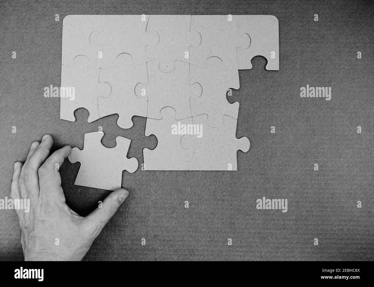 Die Hand des Mannes hängt das fehlende Teil des Puzzles.Schwarz-Weiß-Foto. Stockfoto