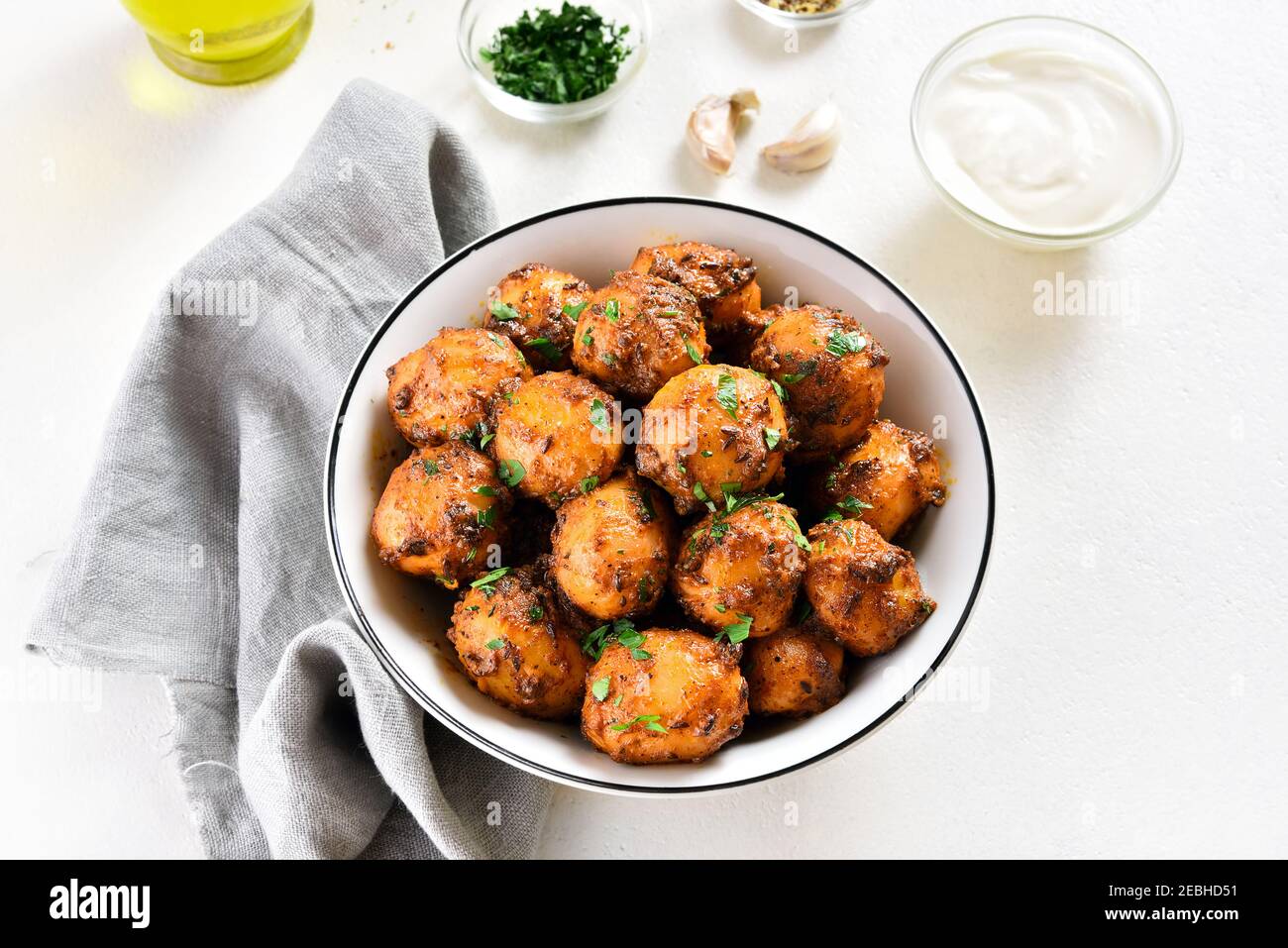 Bombay Potatoes. Gebratene kleine Babykartoffeln mit Jeera-Samen und Koriander in einer Schüssel auf hellem Hintergrund. Indische Gerichte. Stockfoto