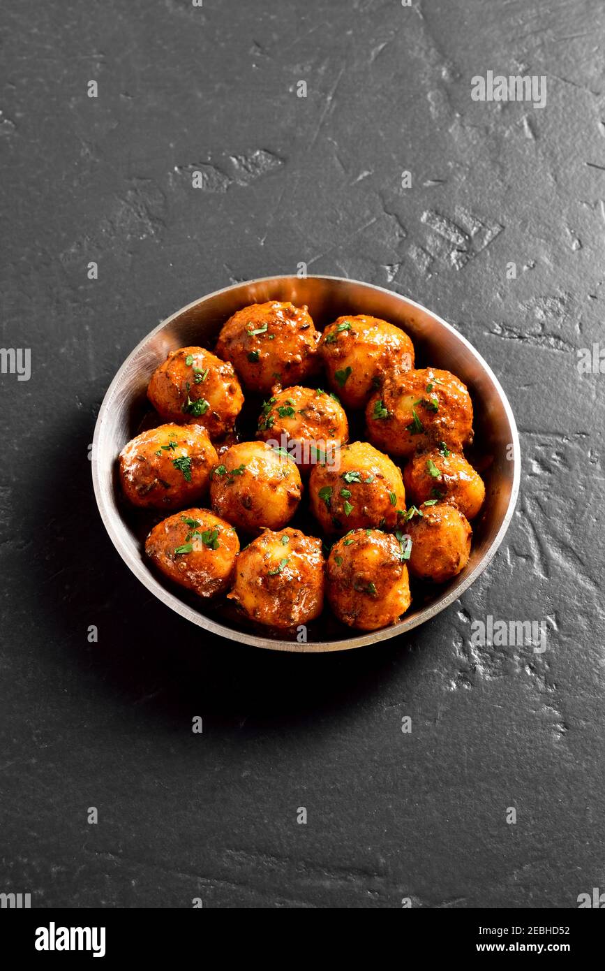 Bombay Potatoes. Gebratene kleine Babykartoffeln mit Jeera-Samen und Koriander in einer Schüssel auf dunklem Hintergrund mit Freitextbereich. Stockfoto