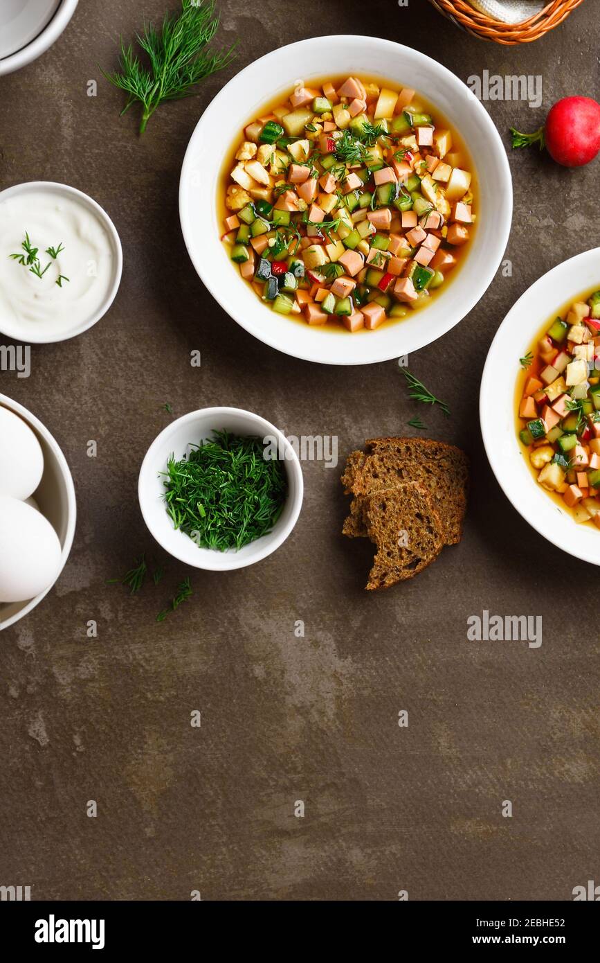 Traditionelle kalte russische Suppe Okroschka mit Wurst, Gemüse und Kvass über braunem Steinhintergrund mit freiem Textraum. Leckeres Sommergericht zum Abendessen Stockfoto