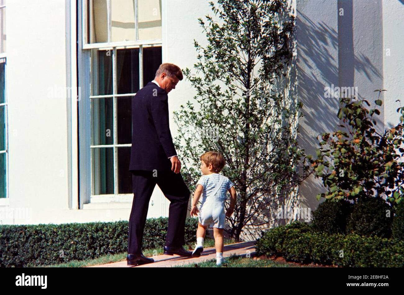 Präsident Kennedy mit John F. Kennedy, Jr. (JFK, Jr.). Präsident John F. Kennedy geht mit seinem Sohn, John F. Kennedy, Jr., vom South Lawn zur West Wing Colonnade des Weißen Hauses, Washington, D.C. Stockfoto