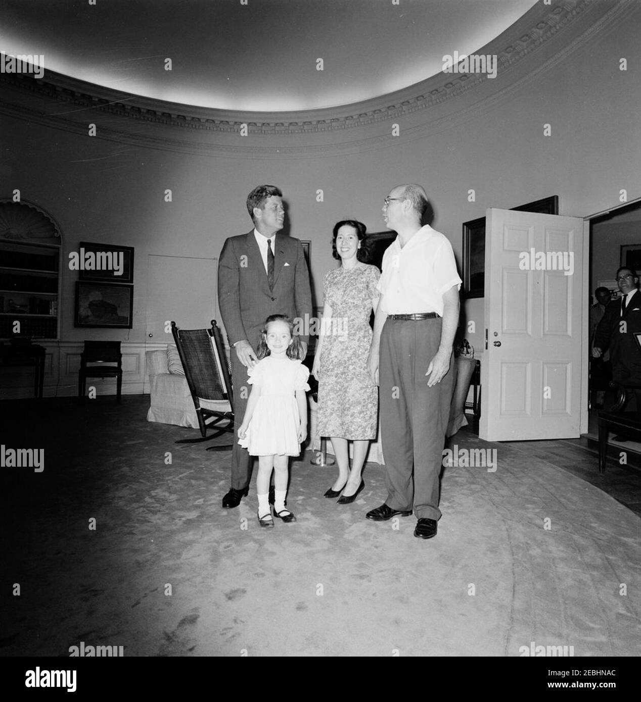 Besuch der 1.000.000th Besucher im Weißen Haus für 1962, William und Eleanor nealy, 11:15am. Präsident John F. Kennedy besucht William G. Nealy, Jr. (rechts), den millionsten Besucher des Weißen Hauses im Jahr 1962, seine Frau Eleanor Carroll Nealy und ihre Tochter Eleanor Nealy. Der Präsidentenassistent John J. McNally steht ganz rechts in der Tür. Oval Office, White House, Washington, D.C. [Kratzer oben links im Bild sind original auf das Negativ.] Stockfoto