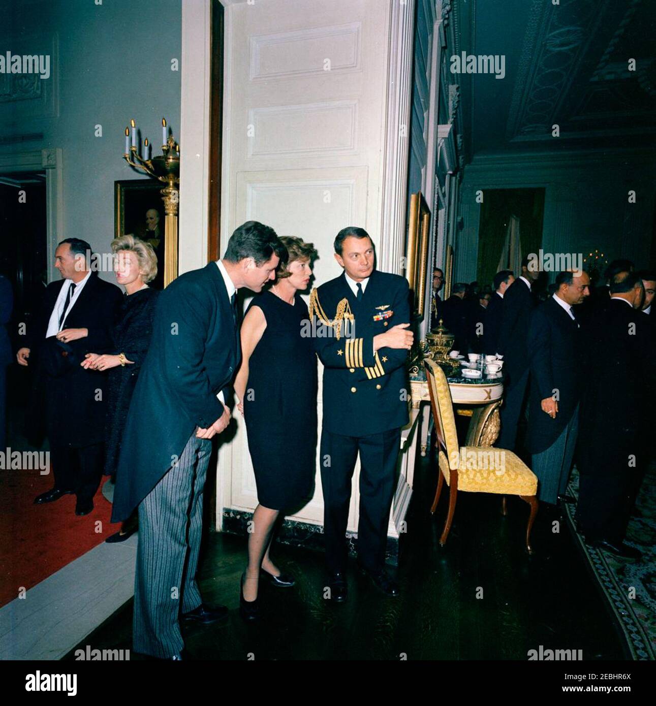 Staatsbegräbnis von Präsident Kennedy: Weißes Haus, nach Beerdigung Empfang. Senator Edward M. Kennedy (Massachusetts) und Eunice Kennedy Shriver sprechen mit Naval Aide zu Präsident John F. Kennedy, Kapitän Tazewell Shepard, während eines Empfangs im Weißen Haus, nach dem Staatsbegräbnis von Präsident Kennedy. Robin Chandler Duke, Ehefrau des US-Protokollchef Angier Biddle Duke, steht links von der Tür. State Dining Room, White House, Washington, D.C. Stockfoto