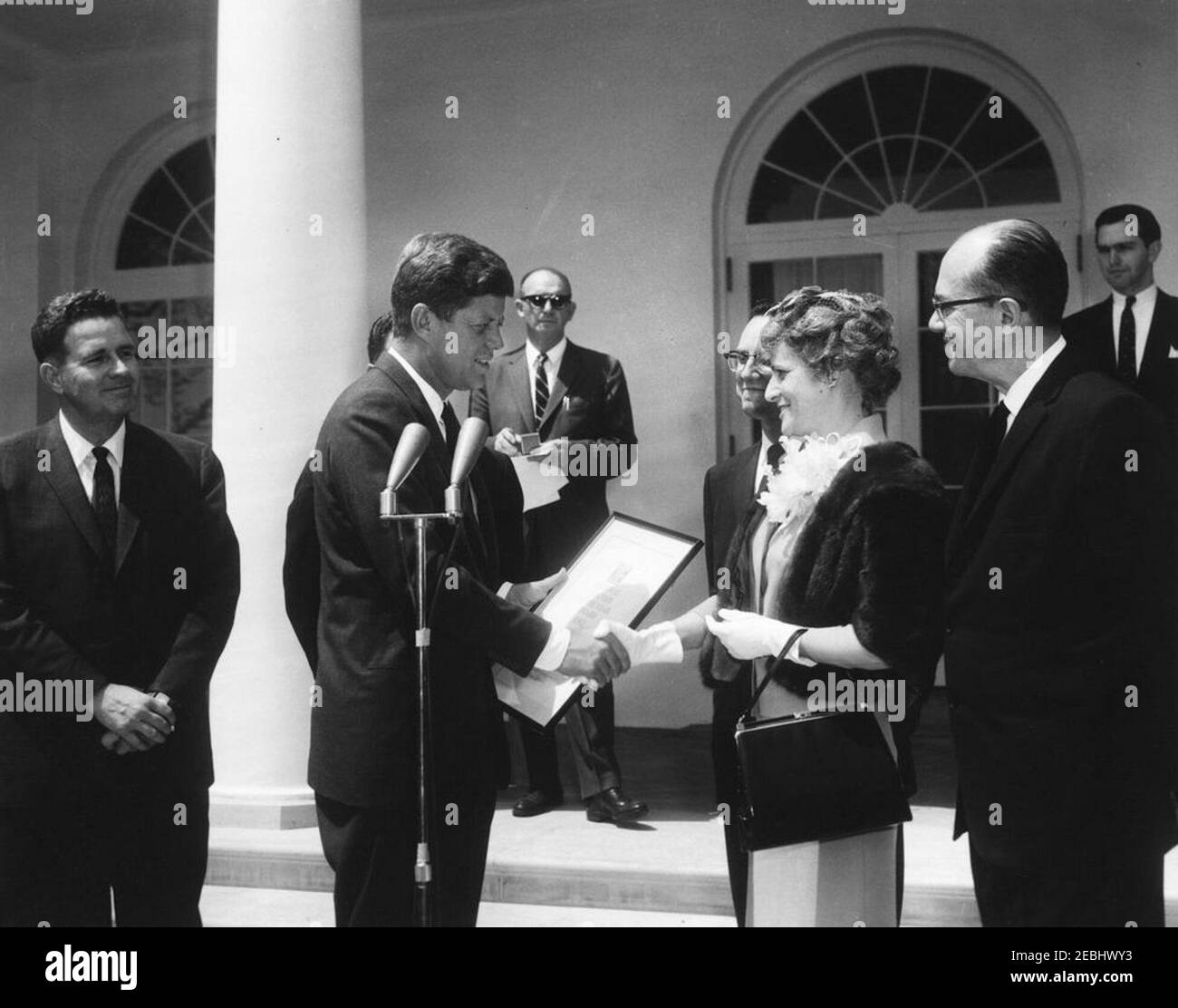 Verleihung des National Teacher of the Year Award an Marjorie L. French aus Topeka, Kansas, 11:55am Uhr. Präsident John F. Kennedy schüttelt die Hände mit Marjorie L. French, von Topeka, Kansas, nachdem er sie mit dem National Teacher of the Year Award (gesponsert vom Council of Chief State School Officers, dem U.S. Office of Education und LOOK Magazine) überreicht hat. Von links nach rechts: Bildungsbeauftragter, Dr. Sterling M. McMurrin; Präsident Kennedy; Sonderassistent des Präsidenten, Dave Powers (im Hintergrund); Frau Frenchu2019s Ehemann, Freeman G. Französisch; Frau Französisch; Exekutivsekretär des C Stockfoto