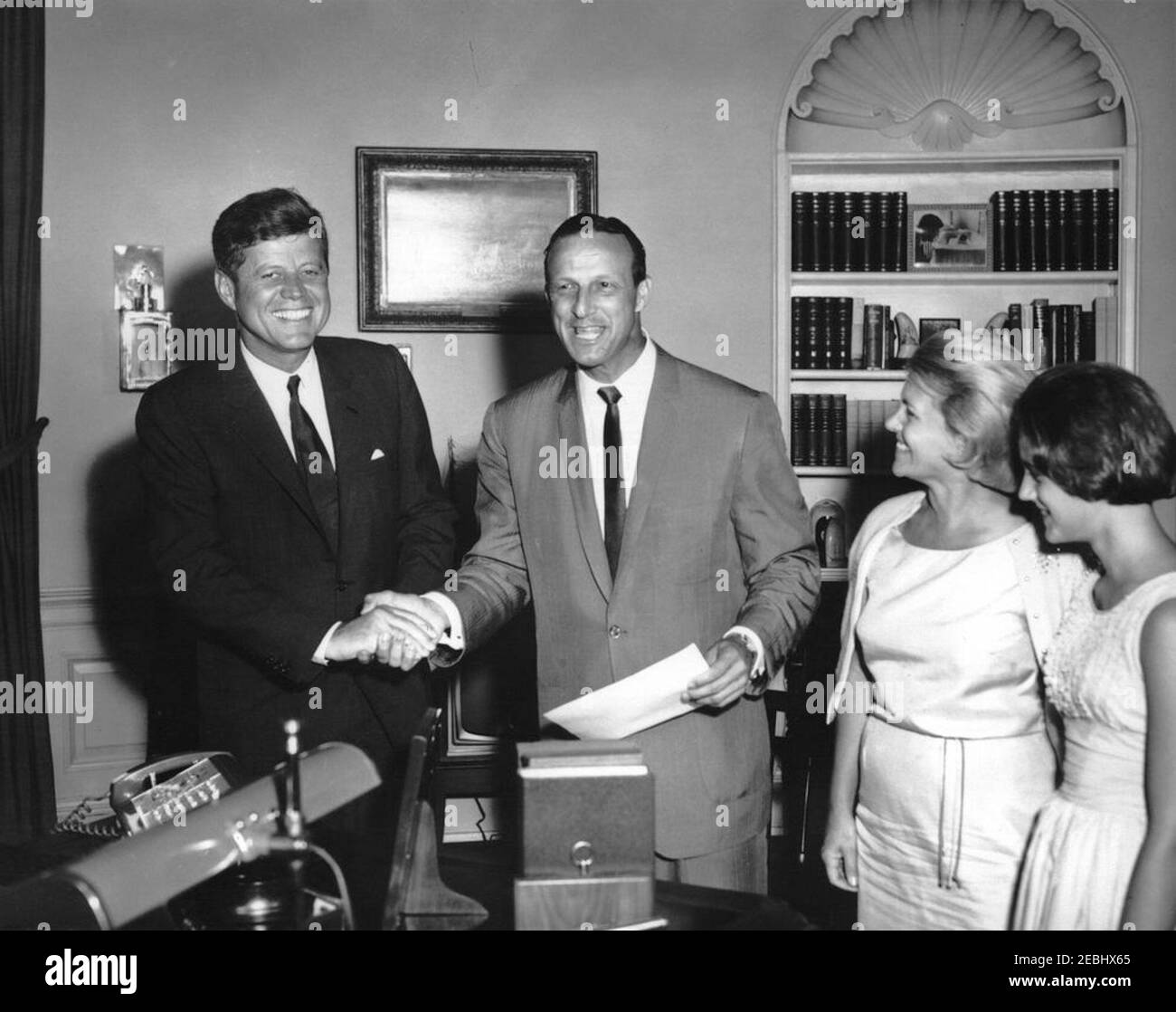 Besuch von Stan Musial, Major League Baseball (MLB) Spieler für die St. Louis Cardinals, und Familie, 4:10pm Uhr. Präsident John F. Kennedy schüttelt sich bei einem Besuch im Oval Office die Hände mit Stan Musial (Mitte), MLB-Spieler der Major League für die St. Louis Cardinals. Seine Frau Lillian Musial und seine Tochter Janet Musial sehen von rechts. White House, Washington, D.C. Stockfoto