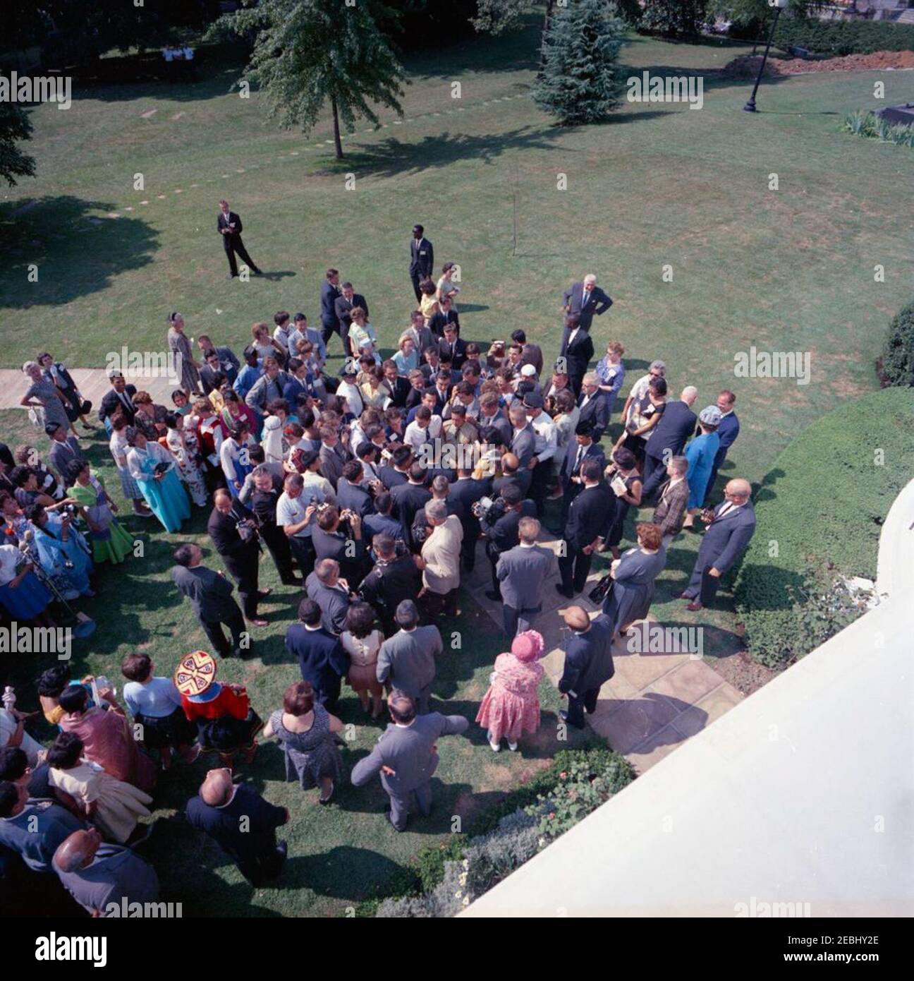 Besuch der internationalen Vertreter des Jr. Roten Kreuzes, 11:00am. Präsident John F. Kennedy (rechts, in Menschenmenge) begrüßt internationale Vertreter des Junior Red Cross auf dem West Wing Lawn. Ebenfalls im Bild: Wochenschau-Fotograf für United Press Movieton, Thomas J. Craven, Sr.; National Park Service (NPS)-Fotograf, Abbie Rowe; Washington-Korrespondent für die Guy Gannet Publishing Company of Maine, May Craig; White House-Korrespondent für United Press International (UPI), Helen Thomas; Geheimagenten des Weißen Hauses, Win Lawson, Walt Coughlin und Don Lawton. Weißes Haus, War Stockfoto