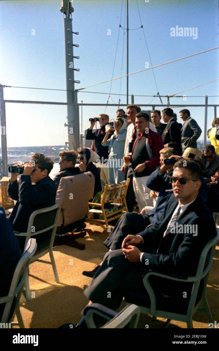 Präsident Kennedy beobachtet das 1st Americau0027s Cup Race. Präsident John F. Kennedy und First Lady Jacqueline Kennedy (beide sitzen links) beobachten das erste Rennen des Cup 1962 Americau0027s von Bord der USS Joseph P. Kennedy, Jr. auch im Bild: John Forbes Kerry; Untersekretär der Marine, Paul u0022Redu0022 Fay; Anita Fay; Franklin D. Roosevelt, Jr.; Pressesekretär Pierre Salinger; Stellvertretender Pressesekretär Malcolm Kilduff; Naval Aide to the President, Captain Tazewell Shepard; Senator Benjamin A. Smith II (Massachusetts); Stellvertretender Finanzminister James A. Reed. Newpo Stockfoto