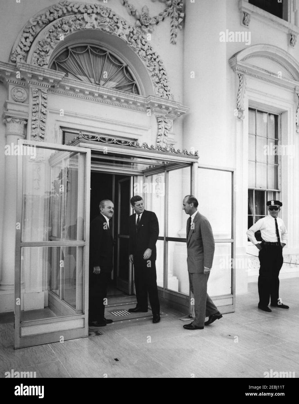 Mittagessen zu Ehren von Guillermo Leon Valencia, designierter Präsident Kolumbiens, 1:00pm Uhr. Präsident John F. Kennedy und der designierte Präsident Kolumbiens, Dr. Guillermo Leu00f3n Valencia (links), betreten das Weiße Haus zu einem Mittagessen zu Ehren des designierten Präsidenten Valencia. US-Chef des Protokolls, Angier Biddle Duke, folgt; ein nicht identifizierter Polizeibeamter des Weißen Hauses steht ganz rechts. North Portico, White House, Washington, D.C. Stockfoto