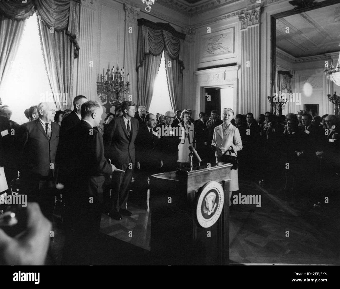 Vorstellung des Berichts der Kommission über die Stellung der Frau an Präsident Kennedy, 4:00pm Uhr. Die stellvertretende Sekretärin für Arbeitsnormen und stellvertretende Vorsitzende der Kommission für die Rechtsstellung der Frauen von Presidentu2019s, Esther Peterson (rechts), hält Bemerkungen bei der Vorstellung des Abschlussberichts der Kommission mit dem Titel u201cAmerican Women,u201d an Präsident John F. Kennedy. Ebenfalls im Bild: Handelsminister Luther H. Hodges; Vizepräsident Lyndon B. Johnson (Gesicht verdeckt); stellvertretender Vorsitzender der Kommission, Dr. Richard A. Lester; Vorsitzender der United States Civil SE Stockfoto