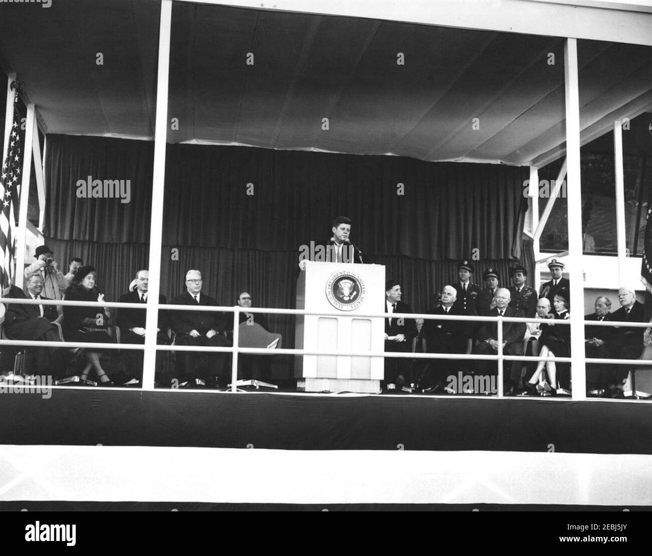 Dedication Ceremonies, Dulles International Airport, 11:12am Uhr. Präsident John F. Kennedy (auf dem Rednerpult) hält Bemerkungen bei der Einweihungszeremonie für den internationalen Flughafen Dulles, benannt nach dem verstorbenen Staatssekretär John Foster Dulles. Auf speakersu0027 Plattform, links von Rednerpult: Ehemaliger Administrator der Federal Aviation Agency (FAA), General Elwood R. u201cPeteu201d Quesada; Janet Avery Dulles (Witwe des ehemaligen Sekretärs Dulles); Staatssekretär, Dean Rusk; Oberster Richter des Obersten Gerichtshofs, Earl Warren; Stellvertretender Administrator der FAA, Generalleutnant Harold W. Grant. Rechts von Stockfoto