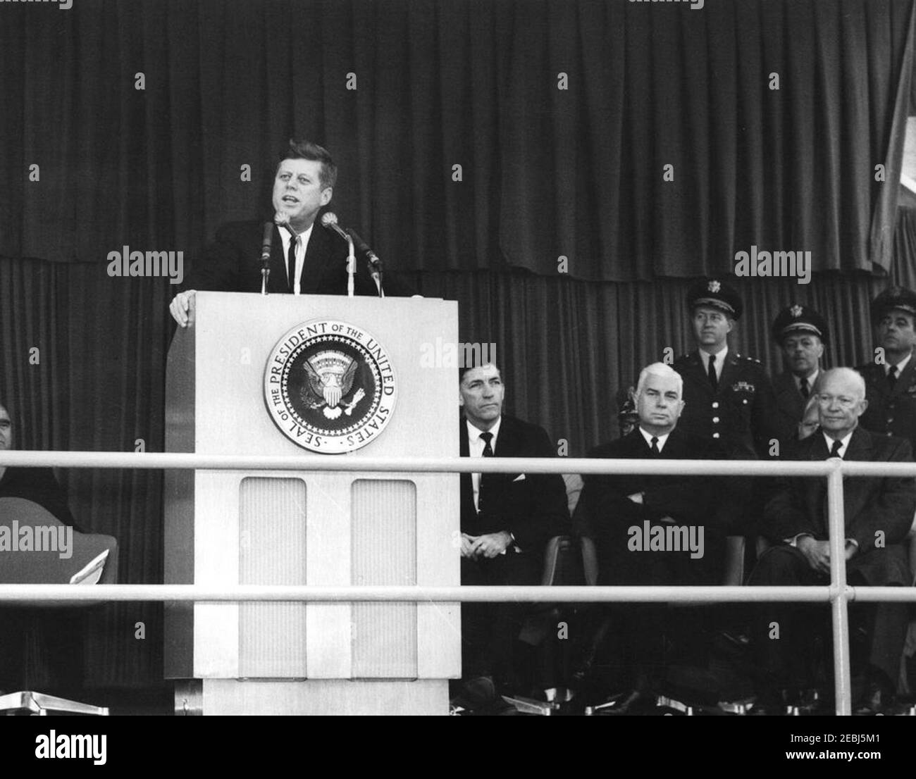 Dedication Ceremonies, Dulles International Airport, 11:12am Uhr. Präsident John F. Kennedy (auf dem Rednerpult) hält Bemerkungen bei der Einweihungszeremonie für den internationalen Flughafen Dulles, benannt nach dem verstorbenen Staatssekretär John Foster Dulles. Auf speakersu2019 Plattform rechts: Administrator der Federal Aviation Agency (FAA), Najeeb Halaby; Gouverneur von Virginia, Albertis S. Harrison, Jr.; Stabschef der United States Air Force, General Curtis E. LeMay; Militärhilfe für den Präsidenten, General Chester V. Clifton; ehemaliger Präsident, General Dwight D. Eisenhower; Direktor des Central Int Stockfoto