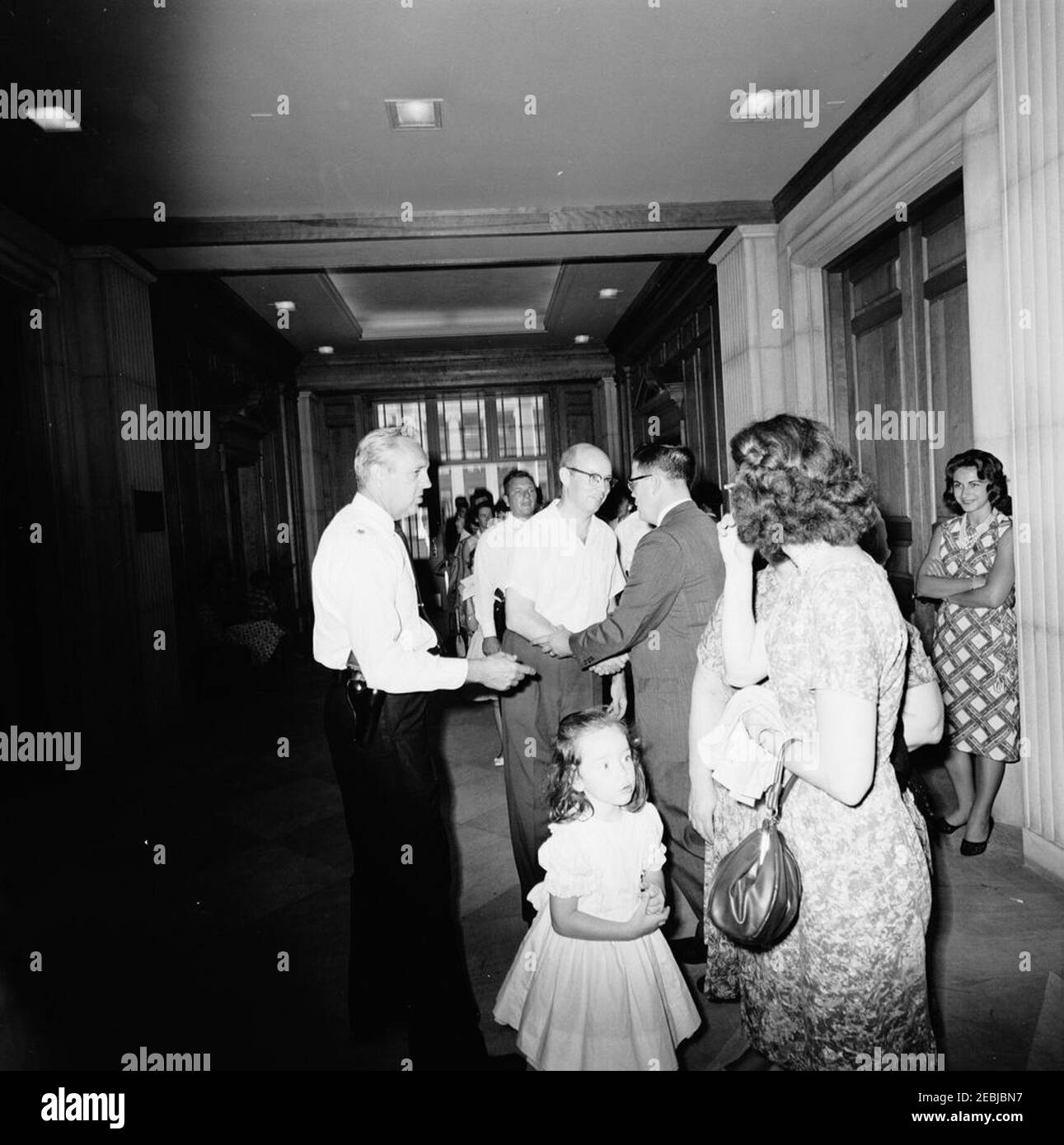 Besuch der 1.000.000th Besucher im Weißen Haus für 1962, William und Eleanor nealy, 11:15am. Der Präsidentenassistent John J. McNally (zurück zur Kamera) begrüßt William G. Nealy, Jr. (Mitte rechts), den einmillionsten Besucher des Weißen Hauses im Jahr 1962, und seine Familie in der Lobby des Ostflügels. Eleanor Carroll nealy (zurück zur Kamera) und ihre Tochter Eleanor nealy stehen im Vordergrund rechts; Chef der Polizei des Weißen Hauses, Major Ralph C. u0022Smokeyu0022 Stover, steht links. White House, Washington, D.C. Stockfoto