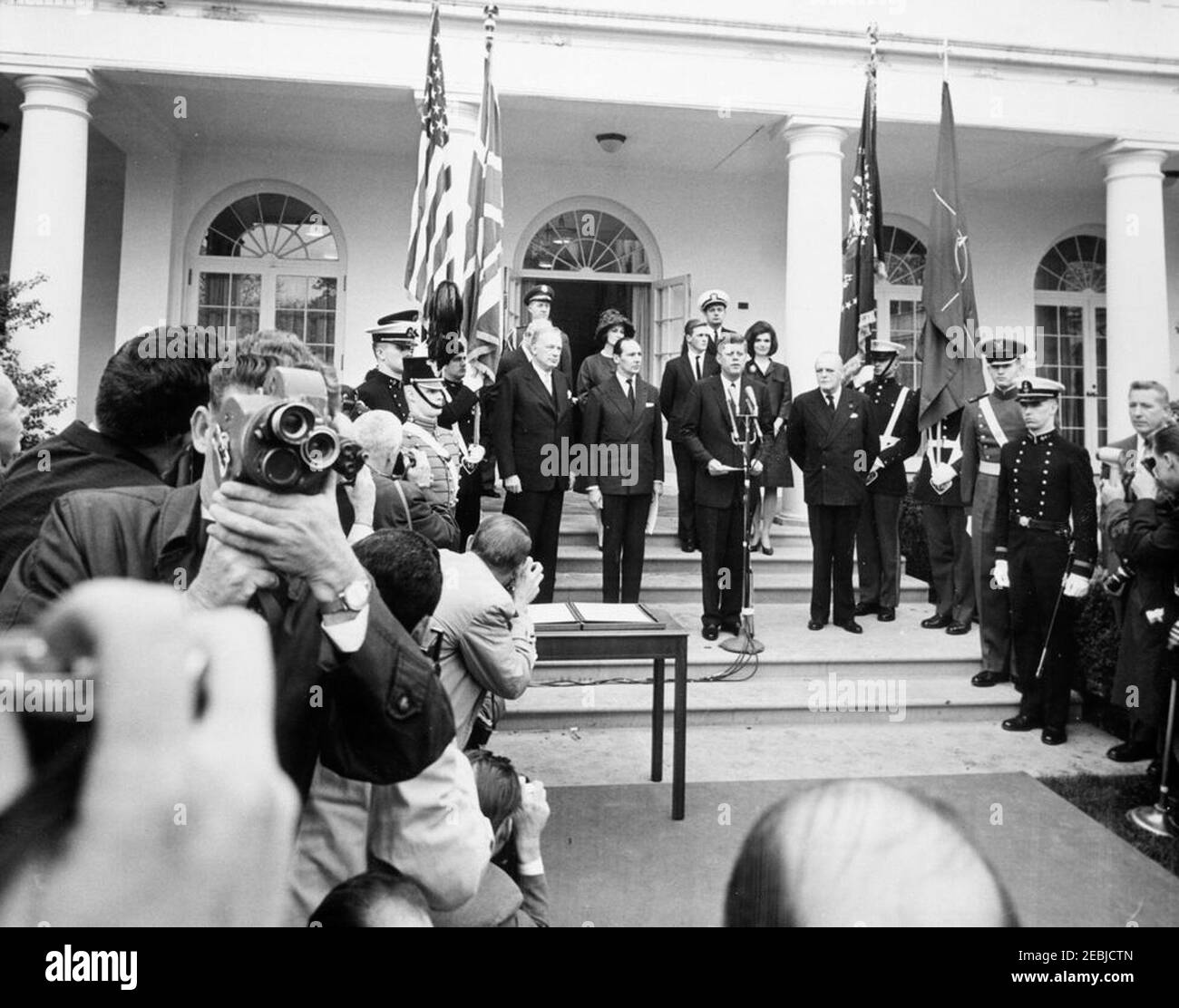 Unterzeichnungszeremonie, Proklamation, die Sir Winston Churchill zum Ehrenbürger der Vereinigten Staaten erklärt, 2:50pm. Präsident John F. Kennedy hält bei einer Proklamation Rede, in der der ehemalige britische Premierminister Sir Winston Churchill zum Ehrenbürger der Vereinigten Staaten erklärt wird. Auf Stufen stehend, erste Reihe (L-R): Unterstaatssekretär George Ball; Botschafter Großbritanniens, Sir David Ormsby-Gore; Präsident Kennedy; Randolph Churchill, Sohn von Sir Winston Churchill. Hintere Reihen (L-R): Militärhilfe an den Präsidenten, General Chester V. Clifton (ganz hinten); Sylvia Thomas Ormsby-Gore, Stockfoto