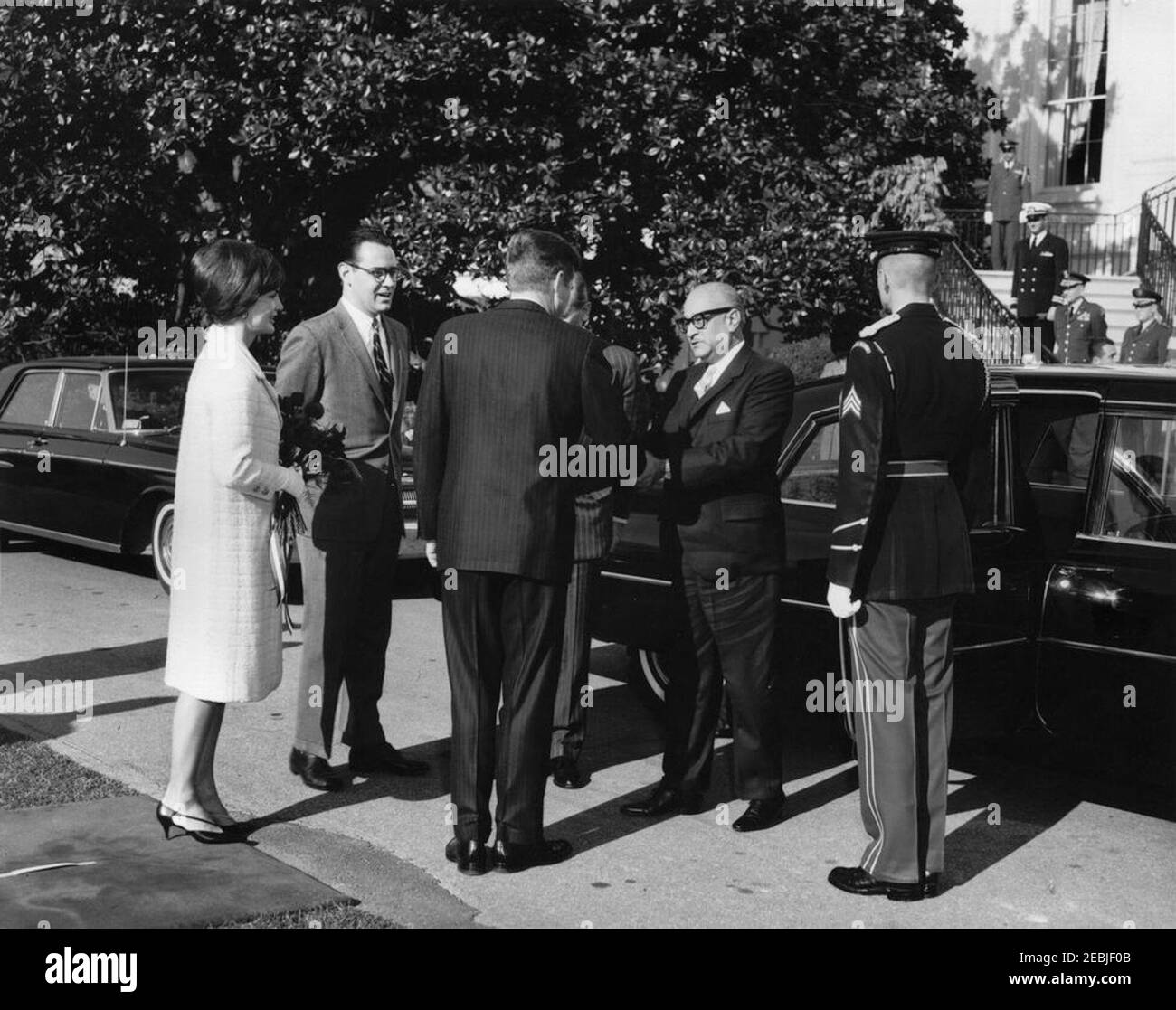 Ankunftszeremonie für Ramon Villeda Morales, Präsident von Honduras, 10:40am Uhr. Präsident John F. Kennedy (zurück zur Kamera) schüttelt die Hände mit Präsident der Republik Honduras, Dr. Ramu00f3n Villeda Morales, nach der Ankunft von Präsident Villeda Moralesu0027s im Weißen Haus. First Lady Jacqueline Kennedy (mit Rosenstrauß) und der Dolmetscher des US-Außenministeriums, Fernando van Reigersberg, blicken von links. South Portico, White House, Washington, D.C. Stockfoto