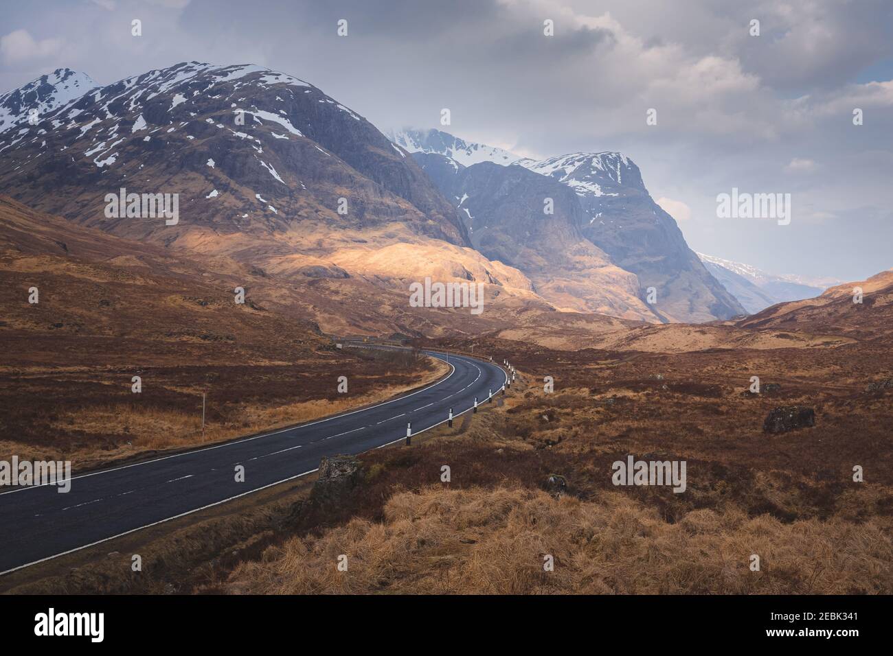 Eine launische Landschaft einer leeren gewundenen Straße von A82 durch Glencoe in den schottischen Highlands zu den Bergkämmen von Beinn Fhada, Gearr Aonach und Aonach Dubh (T Stockfoto
