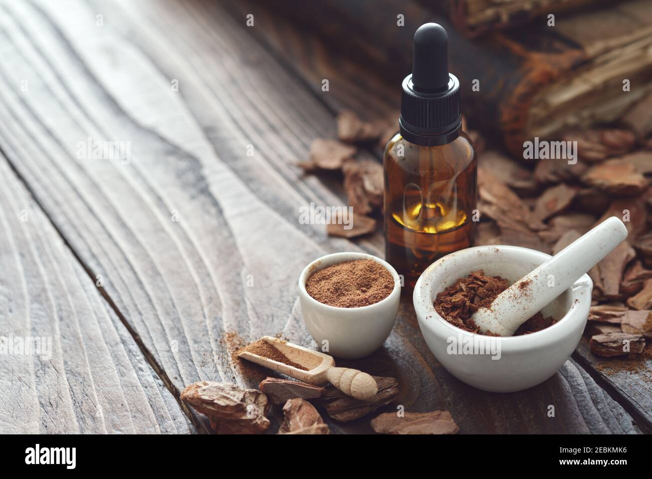 Kiefernrinde, Tinktur oder Ölflasche, Mörser aus pulverförmiger Kiefernrinde und alte Bücher auf dem Hintergrund. Platz für Text kopieren. Stockfoto