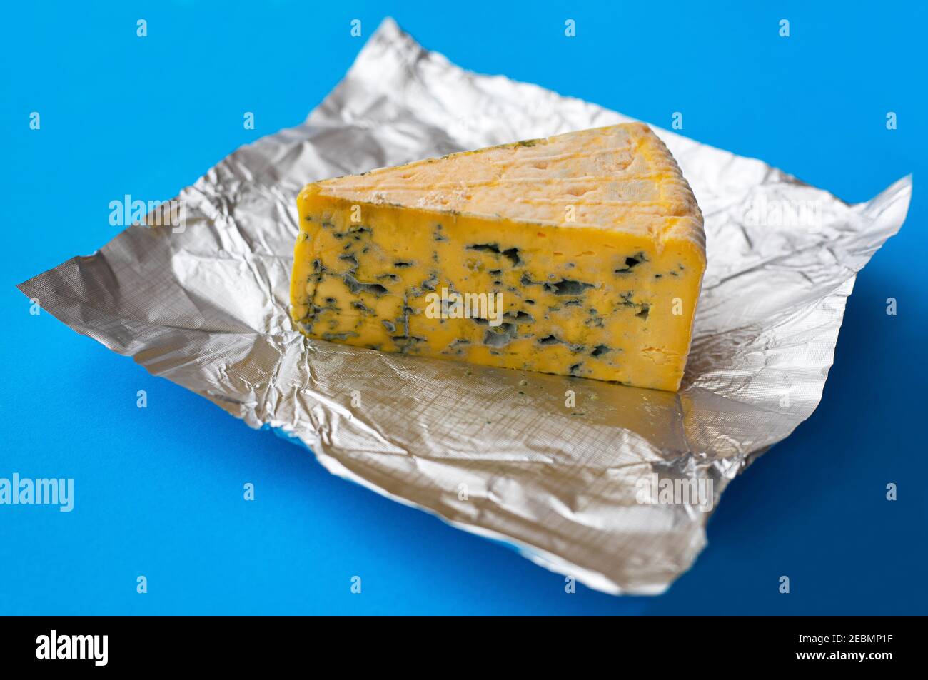 Stück schimmeliger Käse auf blauem Hintergrund Stockfoto