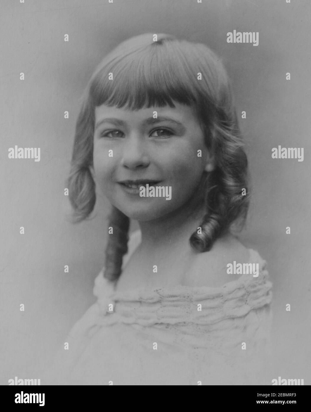 Vintage monochrome Fotografie eines hübschen jungen kaukasischen Mädchen mit Ringel, aus der Edwardianischen Ära 1920s. Stockfoto