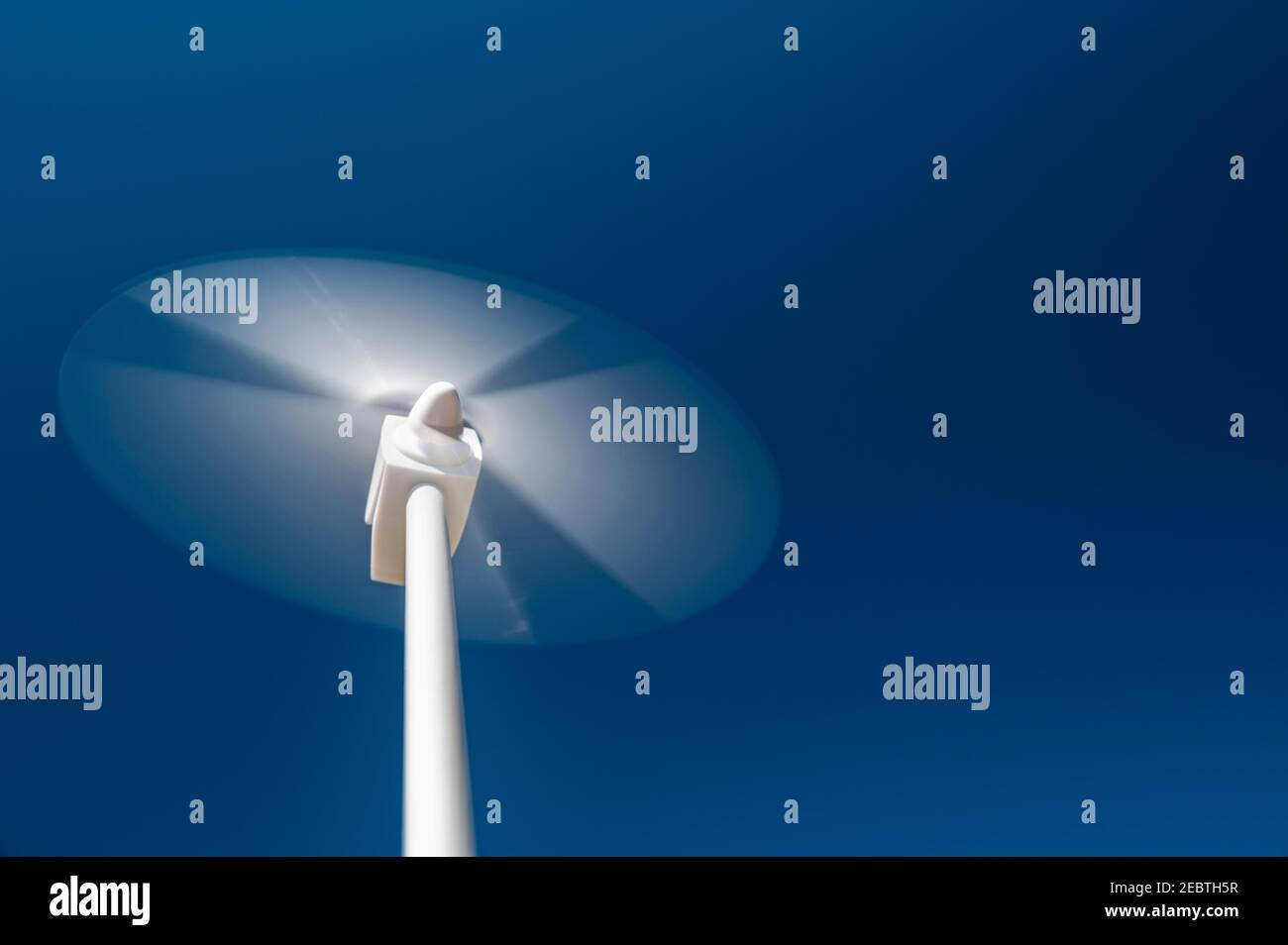 Blick aus dem niedrigen Winkel auf die Windturbine, die sich gegen den blauen Himmel dreht Stockfoto