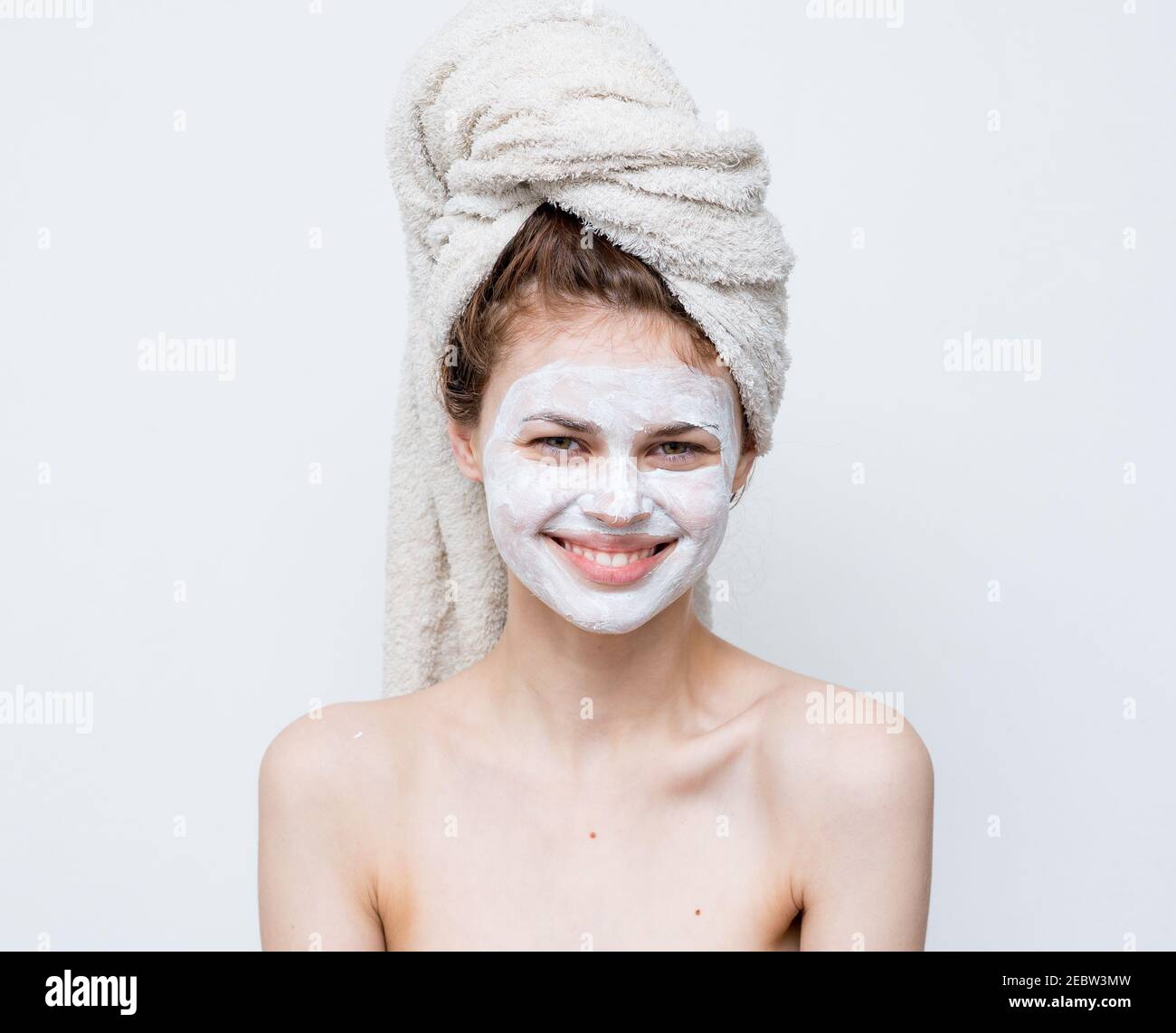 Lustige Frau mit Handtuch auf dem Kopf nackten Schultern weiße Maske