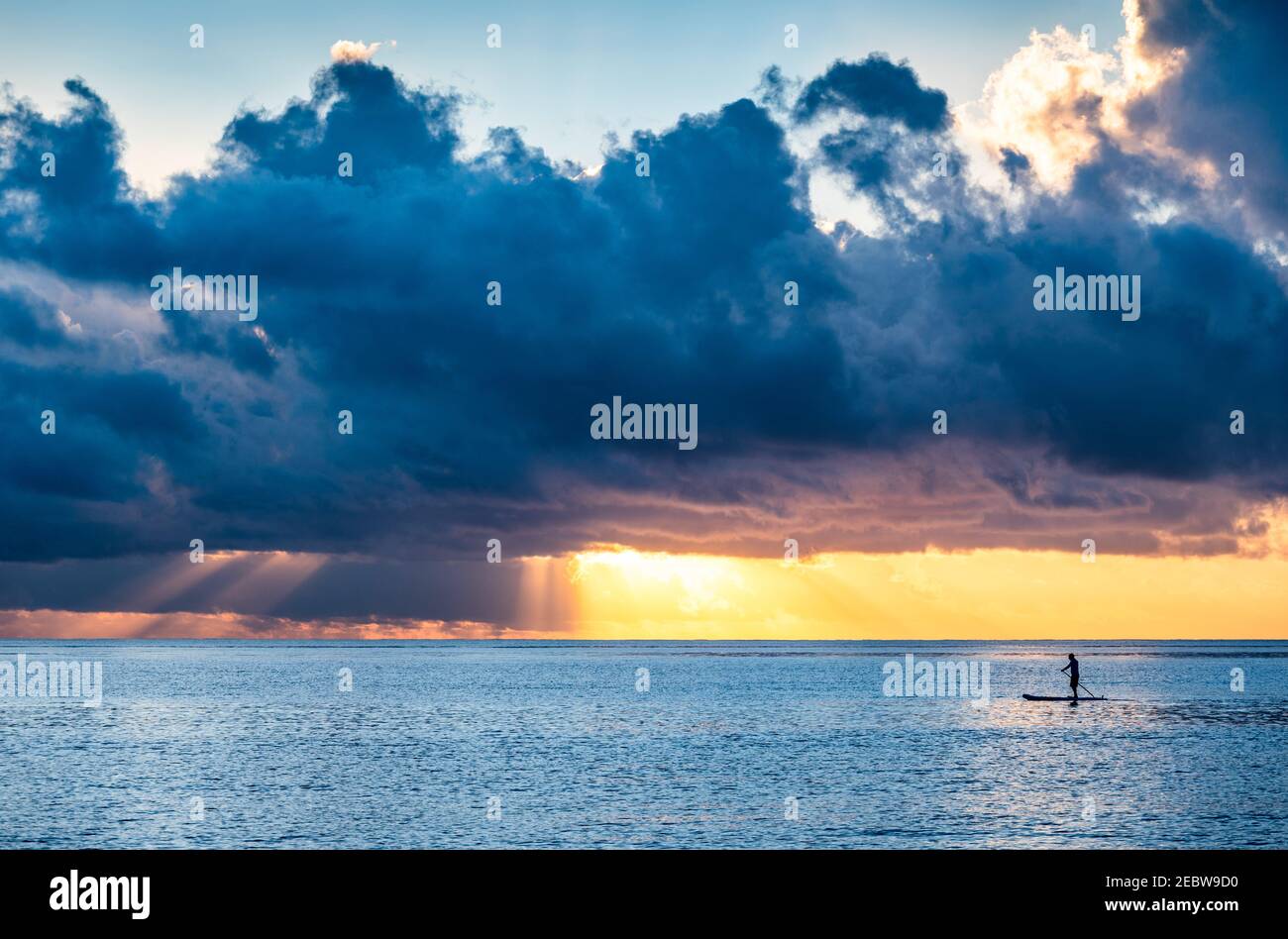 Dramatischer Sonnenuntergang Himmel über Meer mit Silhouette von Person Paddleboarding Stockfoto