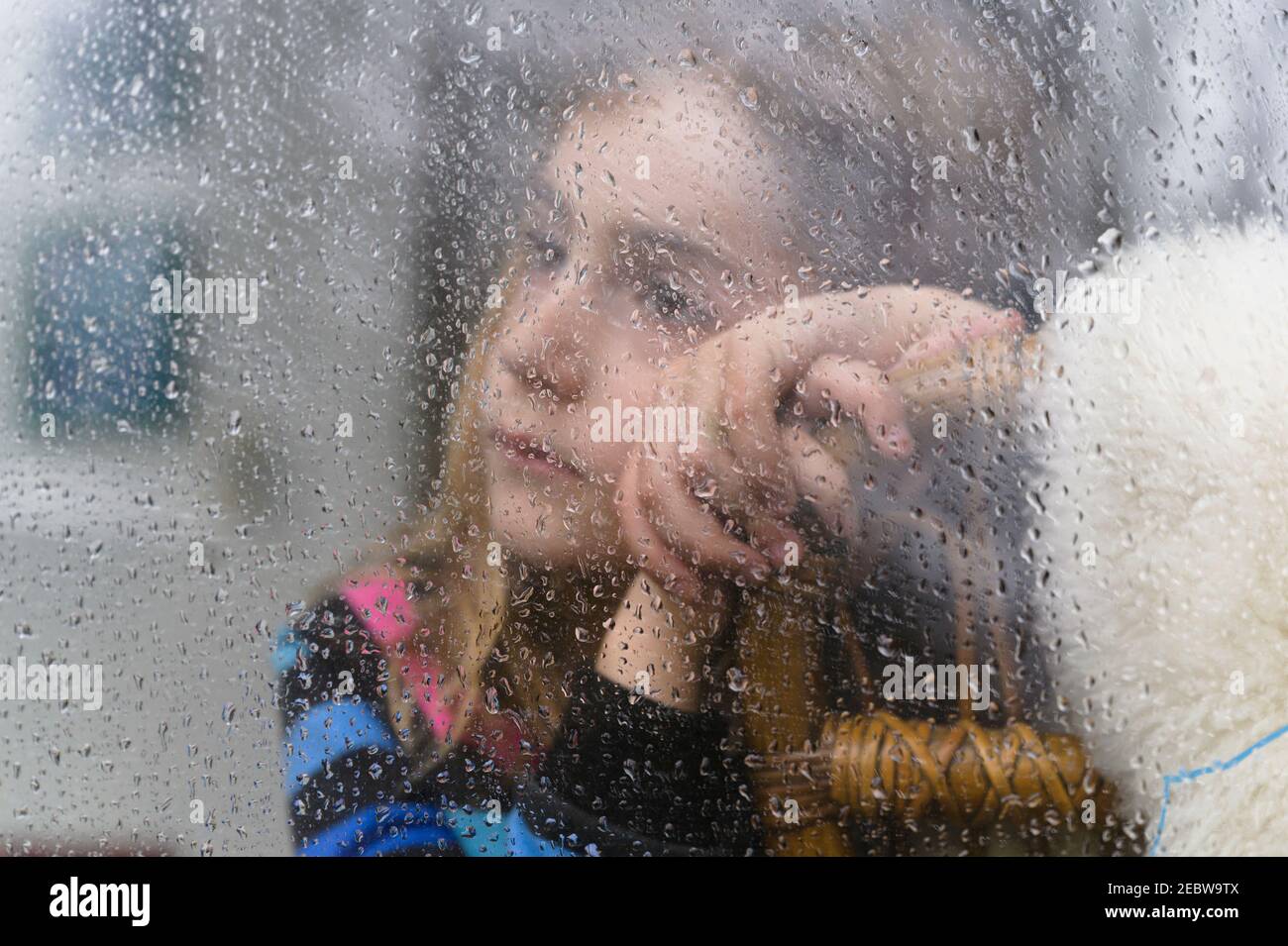 Nahaufnahme eines Mädchens (8-9), das am regnerischen Tag durch das Fenster schaut Stockfoto