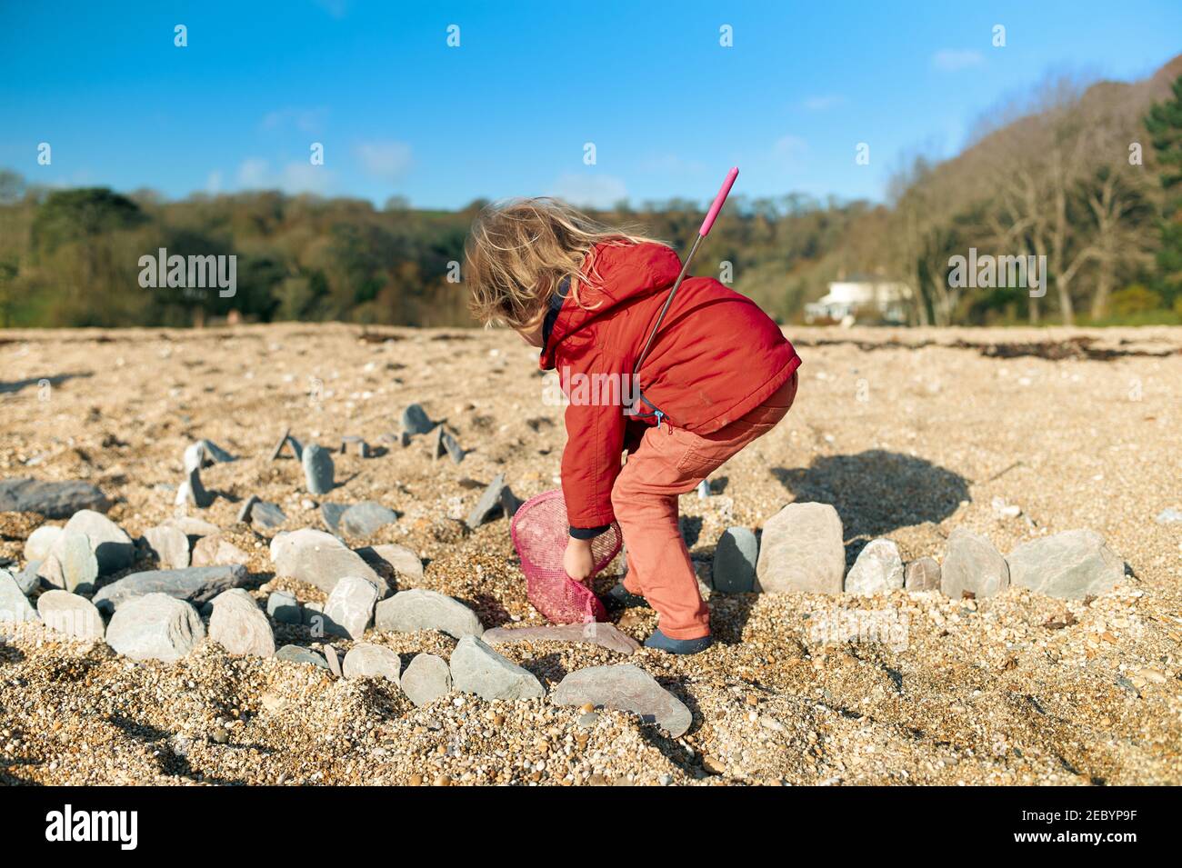Ein kleiner Vorschulkinder spielt am Strand mit Steinen Im Winter Stockfoto