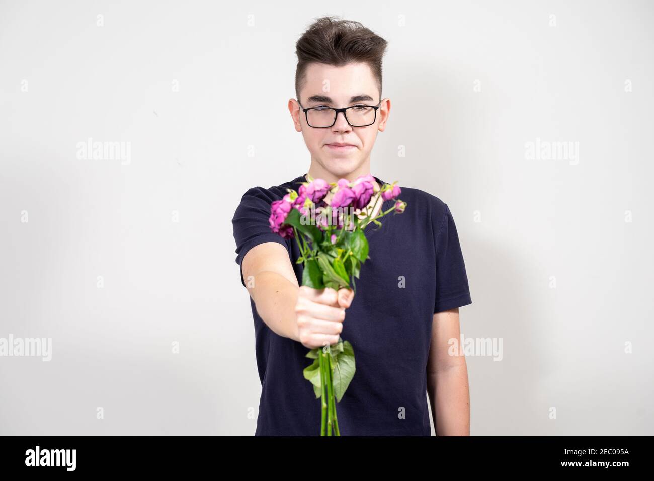 Schüchterner Kerl mit Brille hält einen Strauß verdorrt rosen Stockfoto