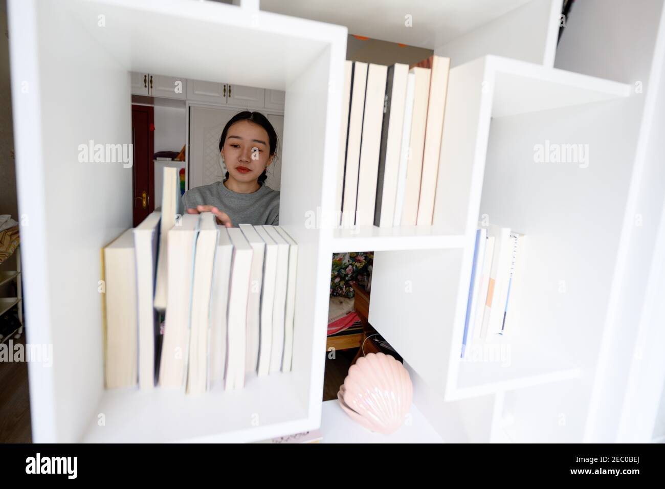 (210213) -- SHANNAN, 13. Februar 2021 (Xinhua) -- Kelyang arrangiert ihr Bücherregal gefüllt mit Literaturbüchern zu Hause in Shannan im Südwesten Chinas Tibet Autonome Region, 10. Februar 2021. Der 12. Februar markiert den ersten Tag des tibetischen Neujahrs, der mit dem diesjährigen Frühlingsfest zusammenfiel. Am frühen Morgen zog Kelyang, 23, traditionelle tibetische Kostüme an und ging mit ihren Eltern zum Gebet durch die Berge.als Postgraduierte-Studentin der Beijing Normal University mit Schwerpunkt auf moderner und zeitgenössischer chinesischer Literatur liebt Kelyang Rap-Musik, schaut sich online Videos an und schreibt Romane. Stockfoto