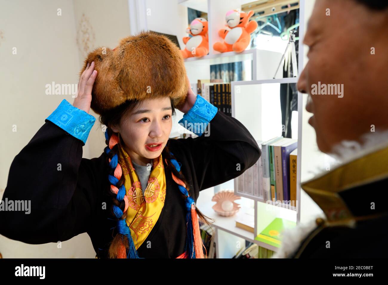 (210213) -- SHANNAN, 13. Februar 2021 (Xinhua) -- Kelyang trägt einen tibetischen Hut in ihrem Haus in Shannan in der Autonomen Region Tibet im Südwesten Chinas, 12. Februar 2021. Der 12. Februar markiert den ersten Tag des tibetischen Neujahrs, der mit dem diesjährigen Frühlingsfest zusammenfiel. Am frühen Morgen zog Kelyang, 23, traditionelle tibetische Kostüme an und ging mit ihren Eltern zum Gebet durch die Berge.als Postgraduierte-Studentin der Beijing Normal University mit Schwerpunkt auf moderner und zeitgenössischer chinesischer Literatur liebt Kelyang Rap-Musik, schaut sich online Videos an und schreibt Romane. Sie lebt ein gewöhnliches Leben l Stockfoto